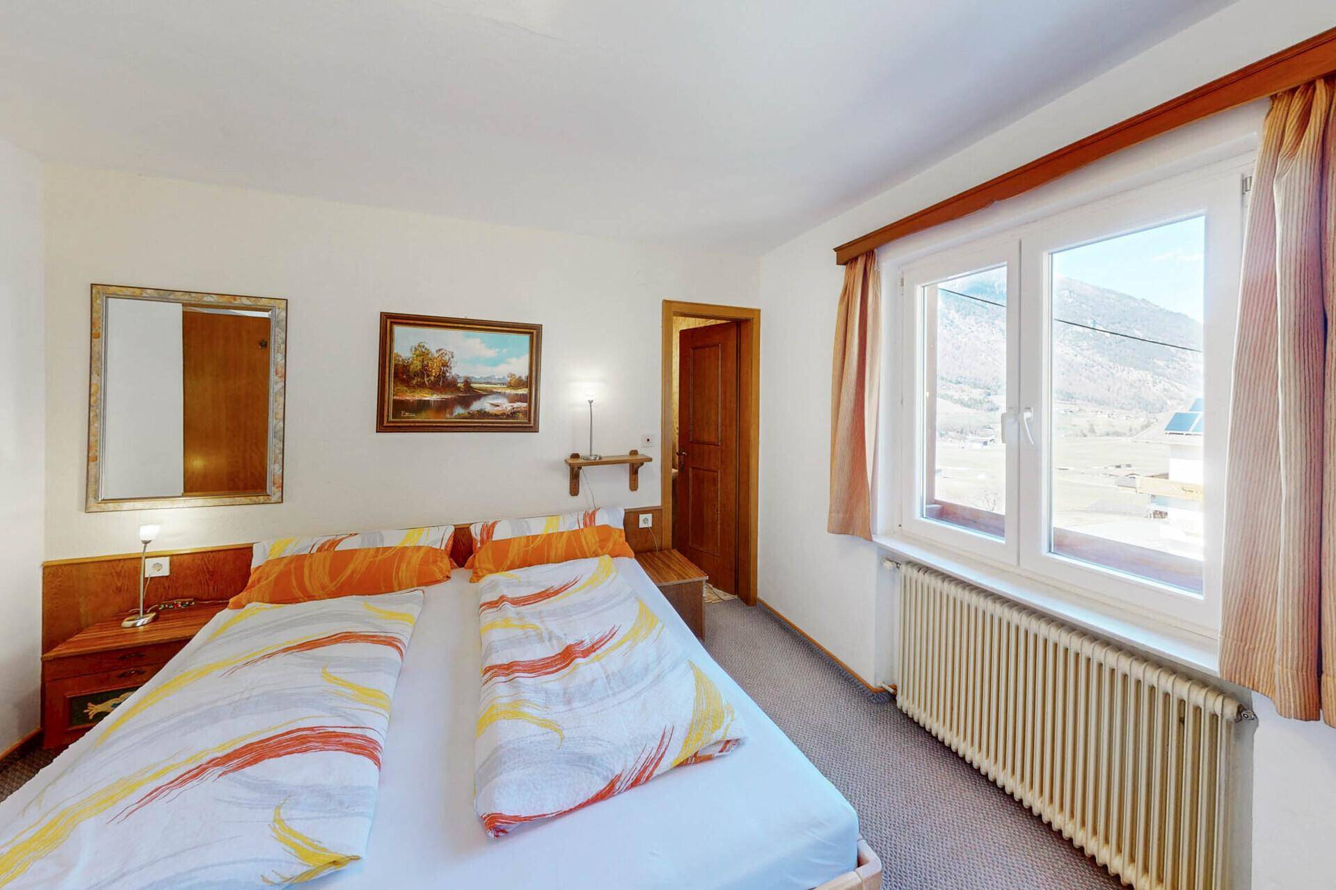 Schlafzimmer mit Doppelbett, Teppichboden und Blick auf die Berge.