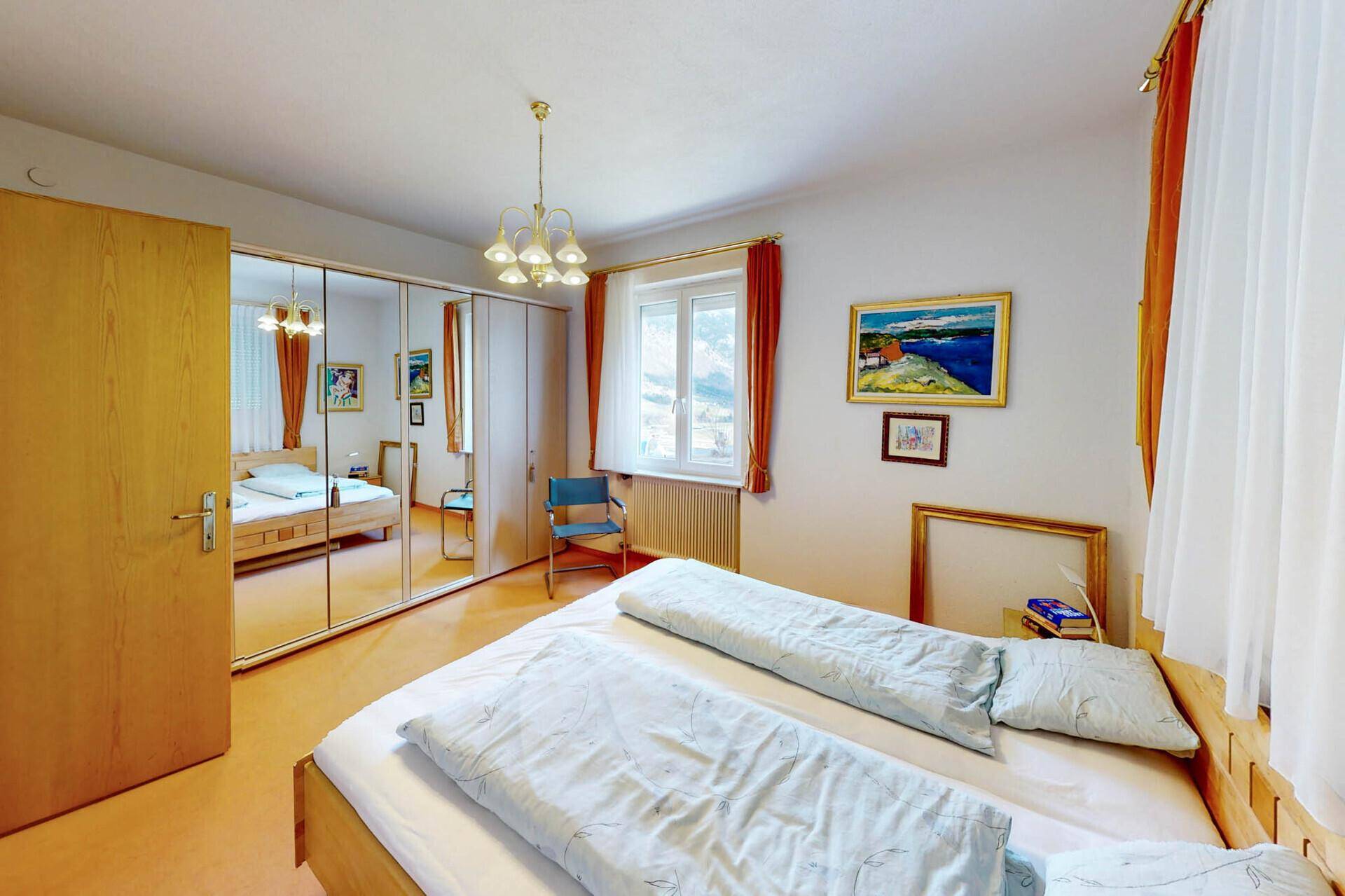 Geräumiges Schlafzimmer mit Spiegelschrank, Doppelbett und Blick ins Grüne.