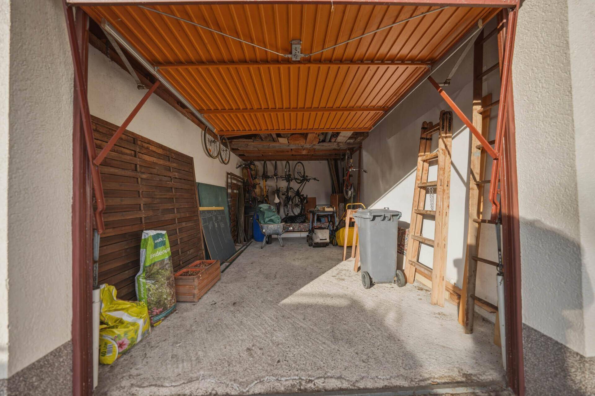 Garage mit offenem Tor, Stauraum und Fahrrädern an der Decke.
