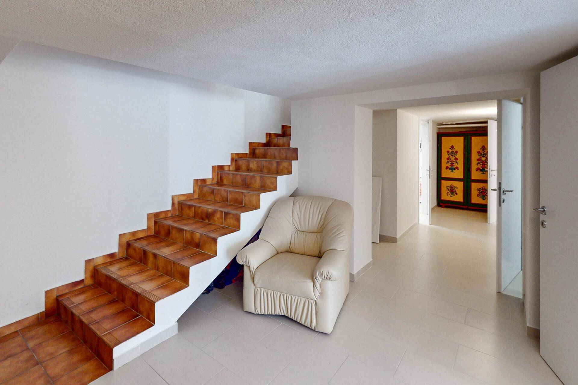 Heller Kellerbereich mit Treppe und Fliesenboden.