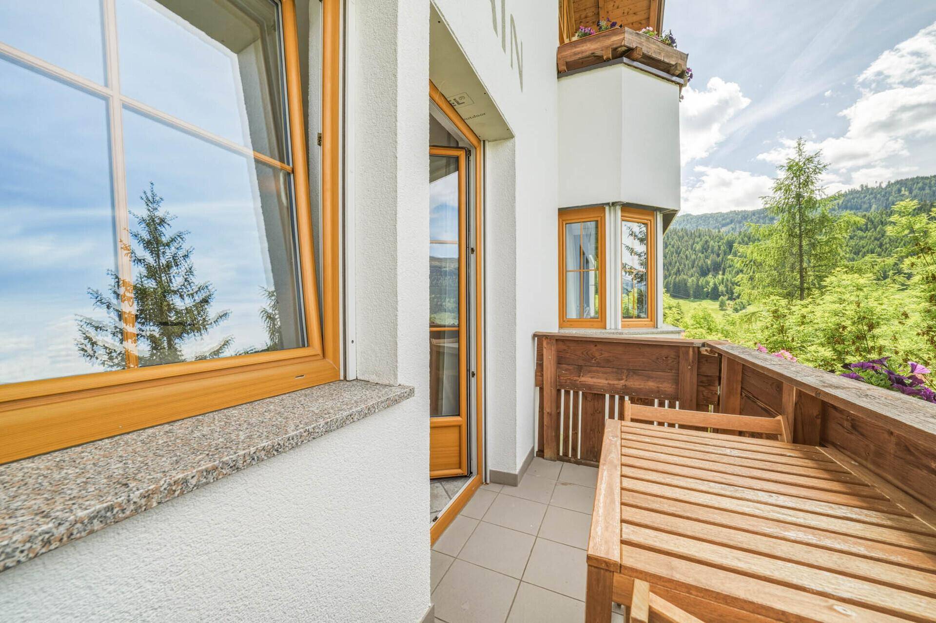 Kleiner Balkon mit Holztisch und Stühlen, ideal für einen Kaffee mit Bergblick.