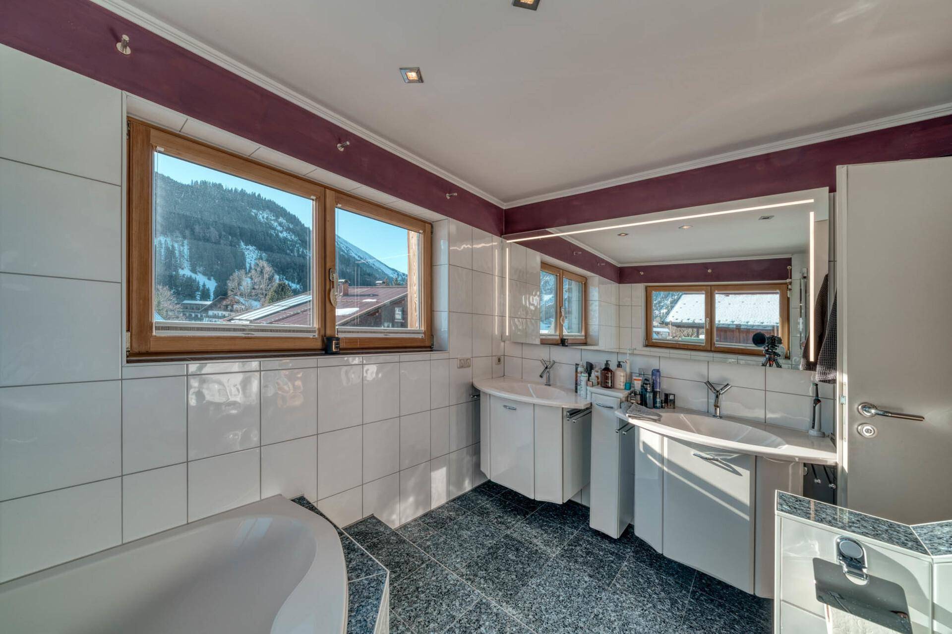 Geräumiges Badezimmer mit Doppelwaschbecken, Badewanne und großem Spiegel.