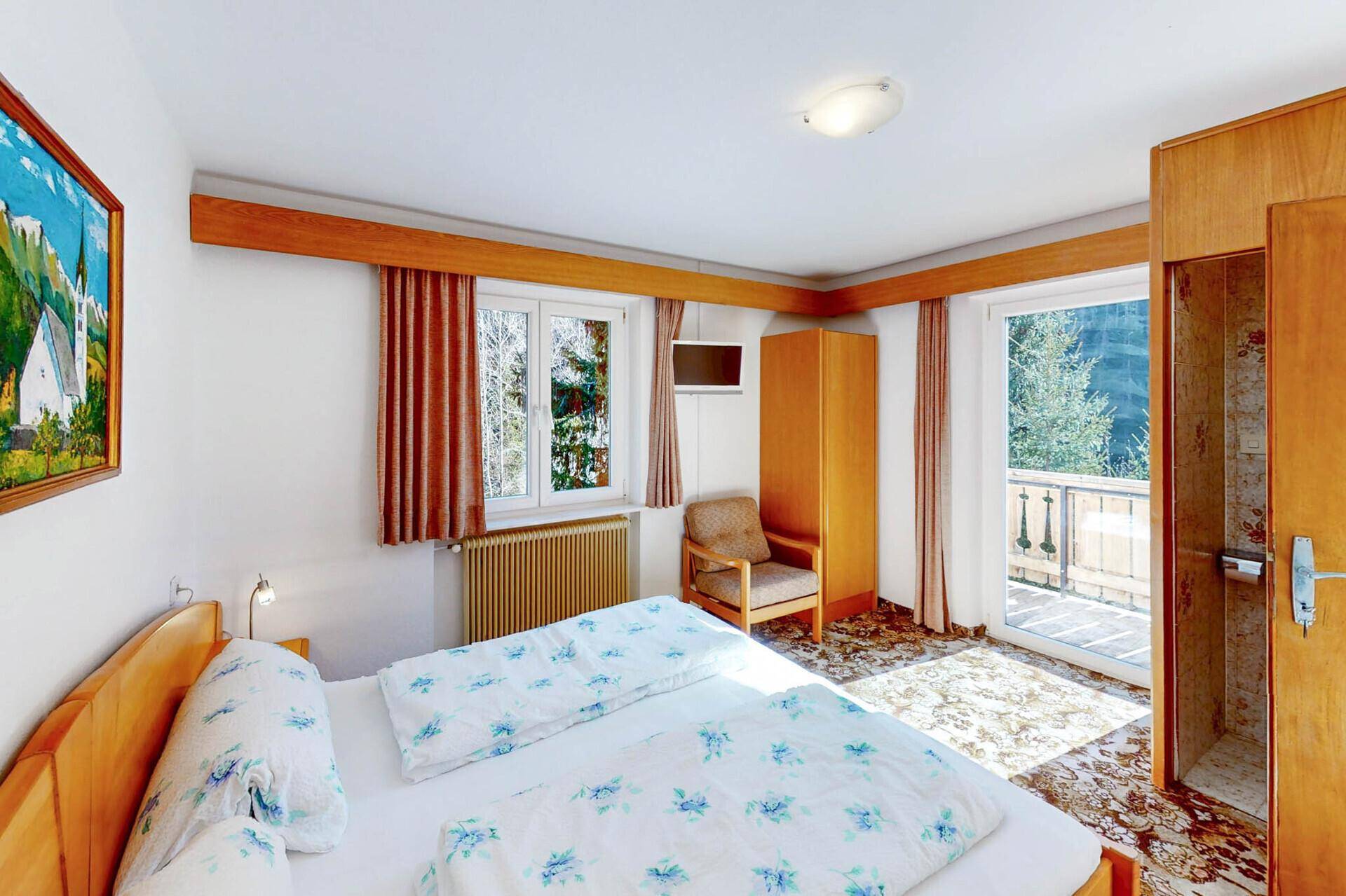 Helles Schlafzimmer mit Doppelbett, Teppichboden und Balkonzugang.