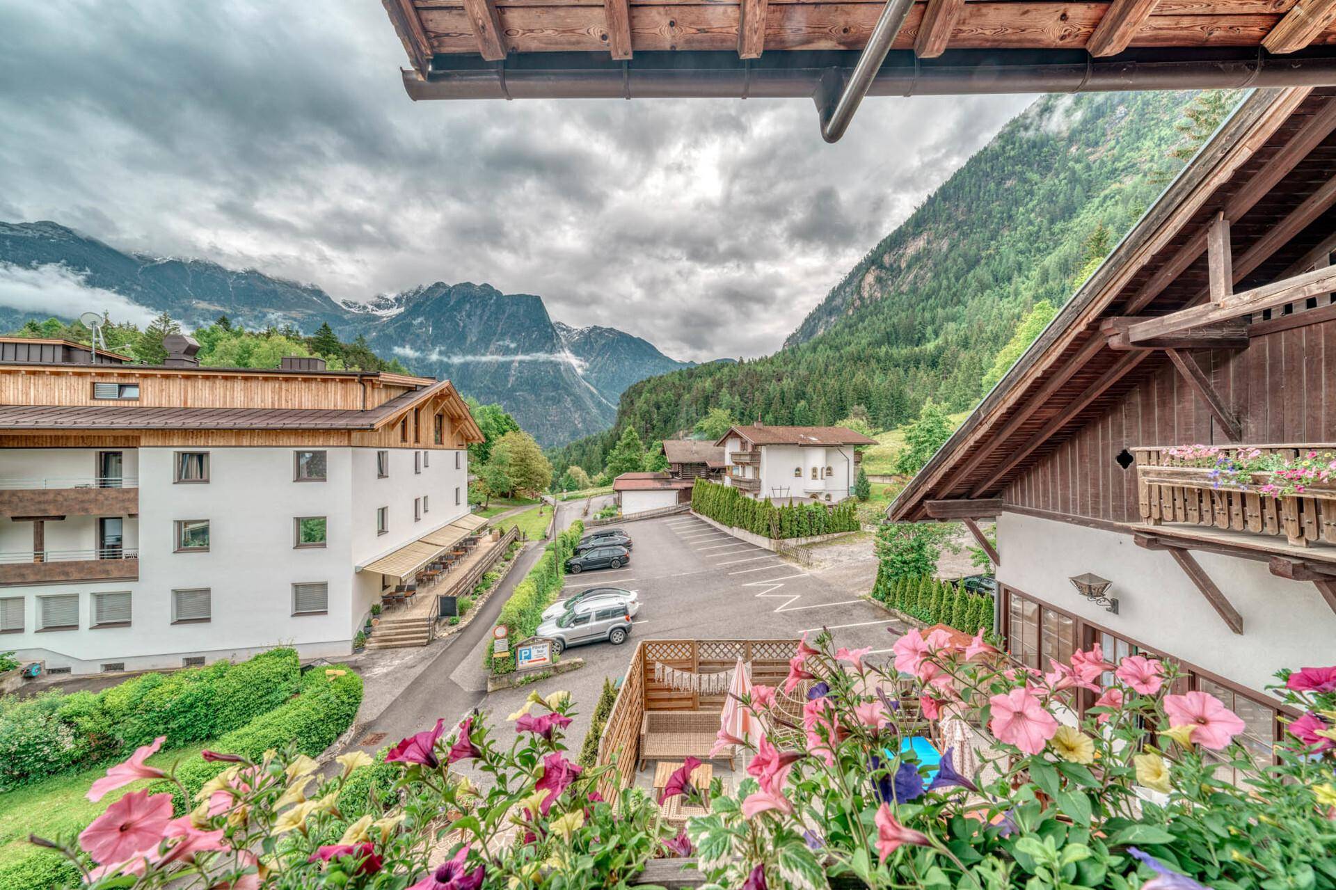 Weitläufiger Blick vom Balkon auf den Parkplatz und die majestätische Bergwelt.