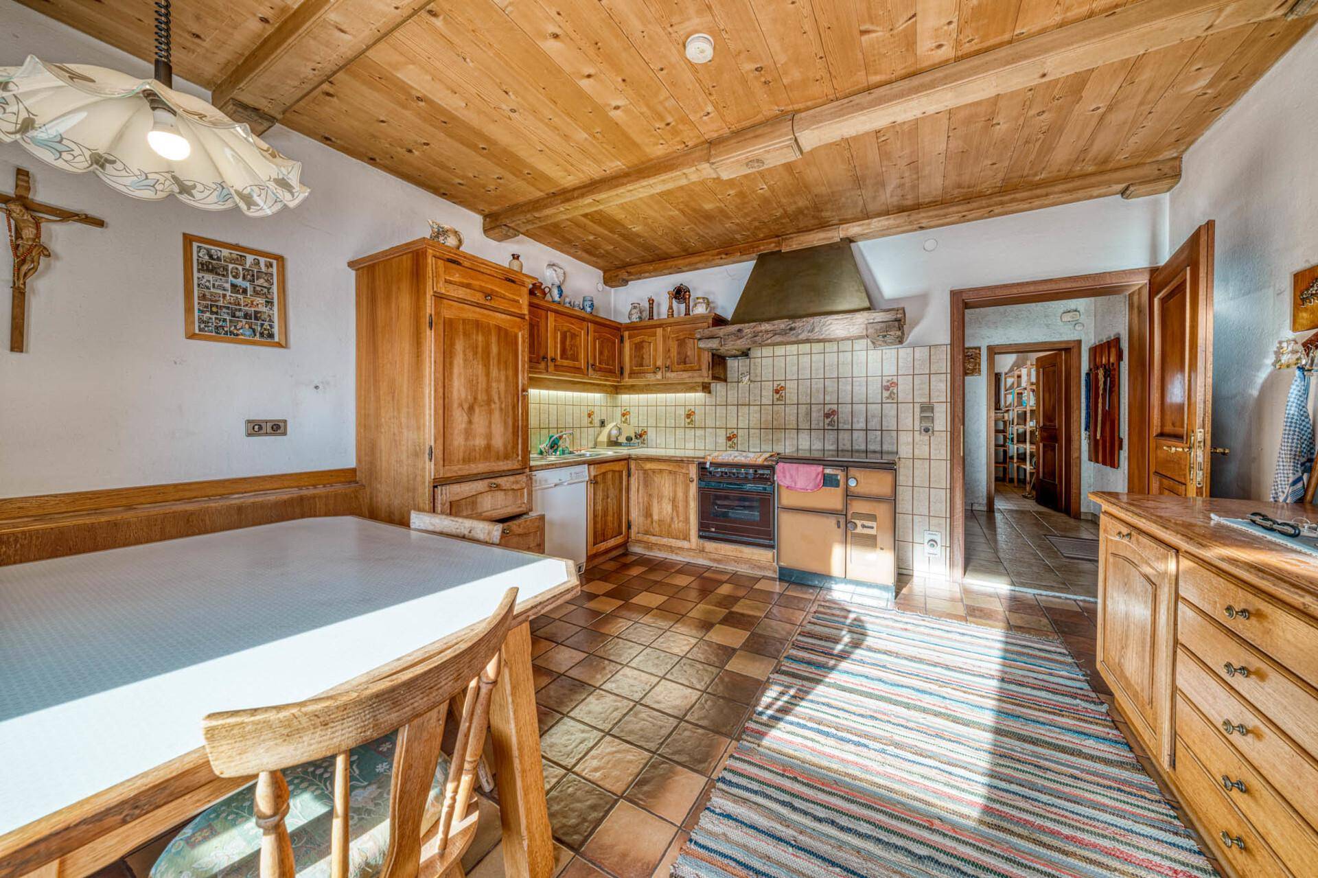 Gemütliche Wohnküche im Landhausstil mit Holzeinbauten, Fliesenboden und Essbereich.