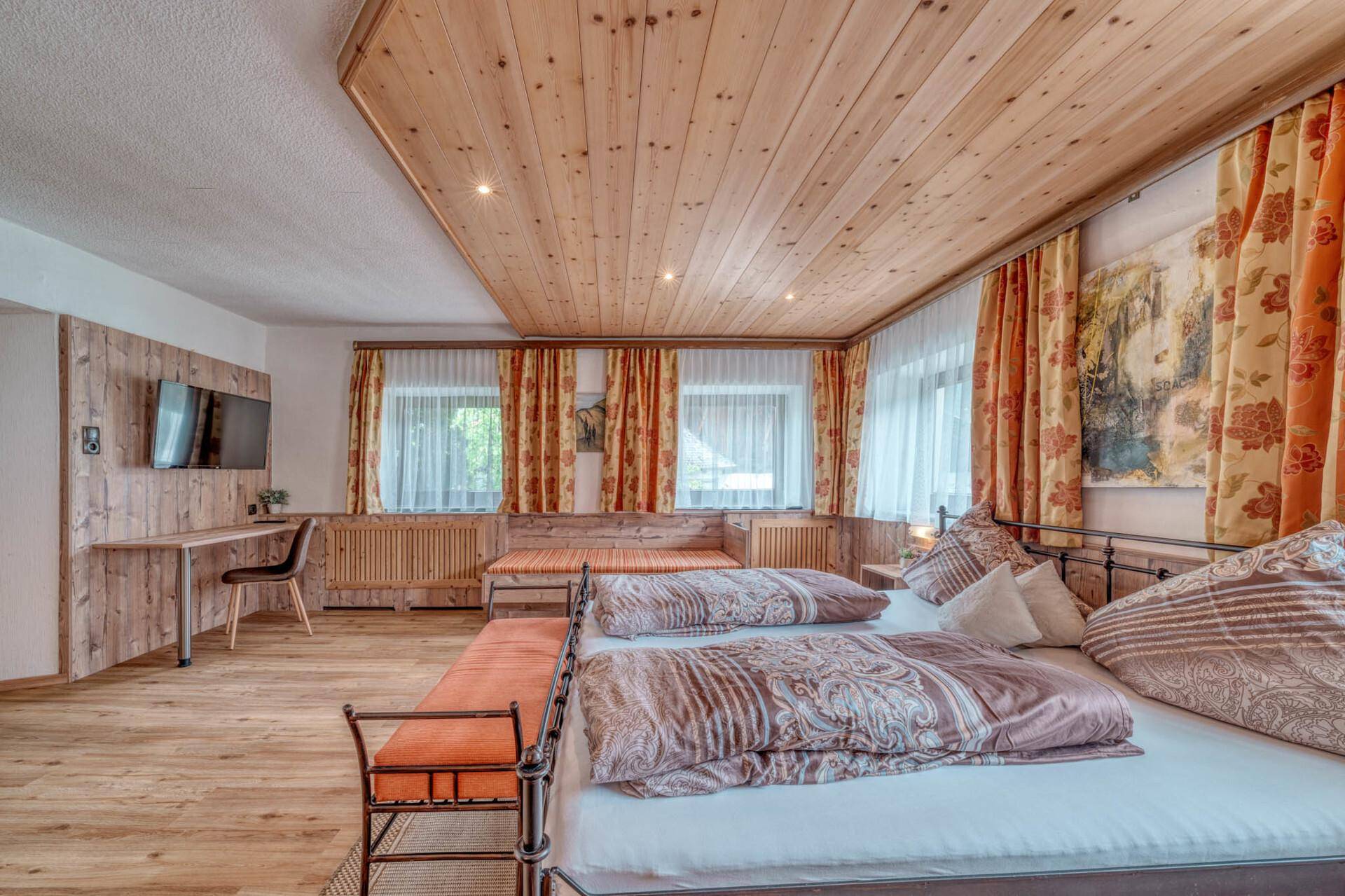Gemütliches Schlafzimmer mit Doppelbett, Holzdecke und traditionellen Vorhängen, hell und einladend.