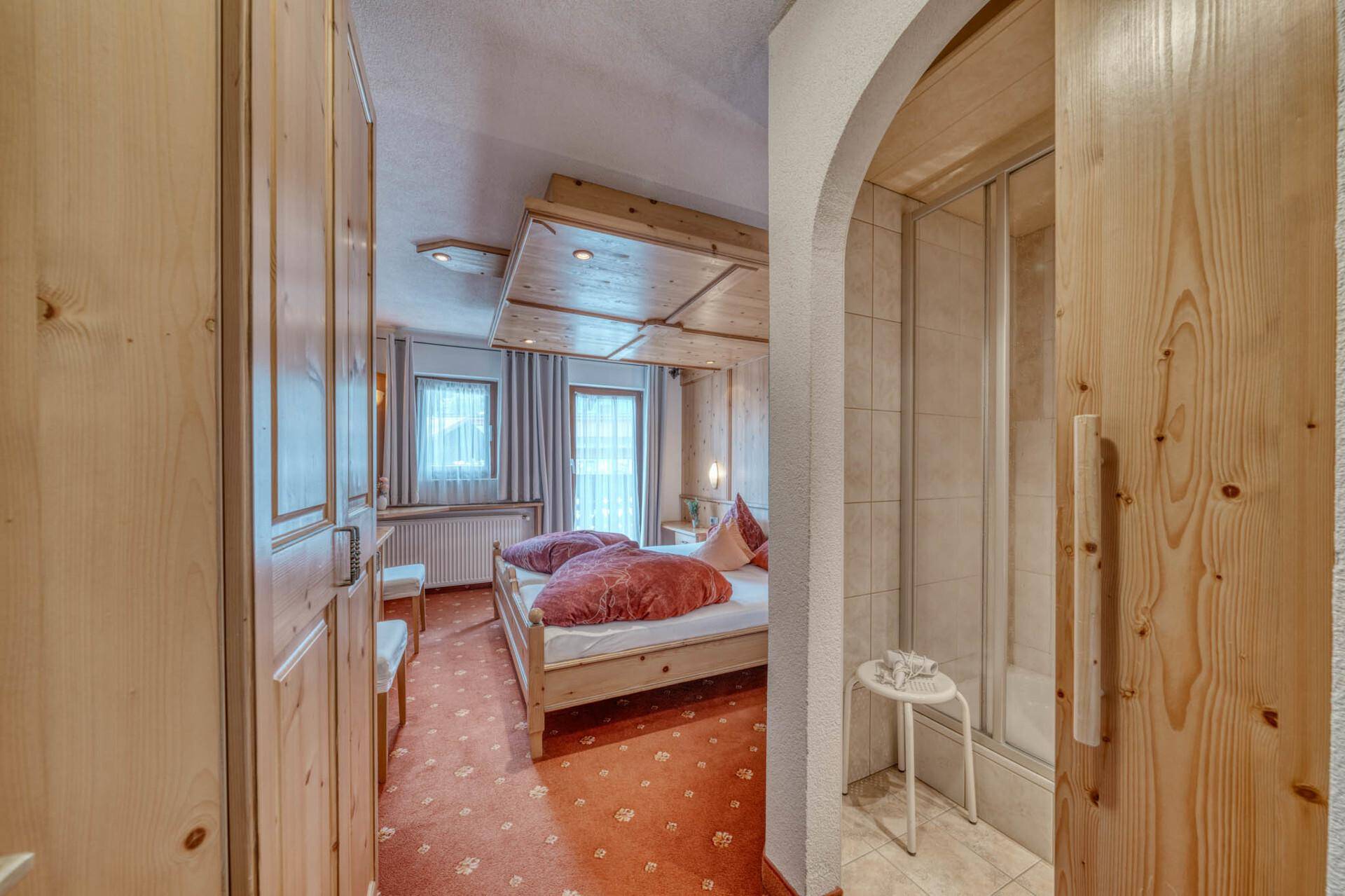 Schlafzimmer mit Holzelementen und Zugang zu einem kleinen Duschbereich.