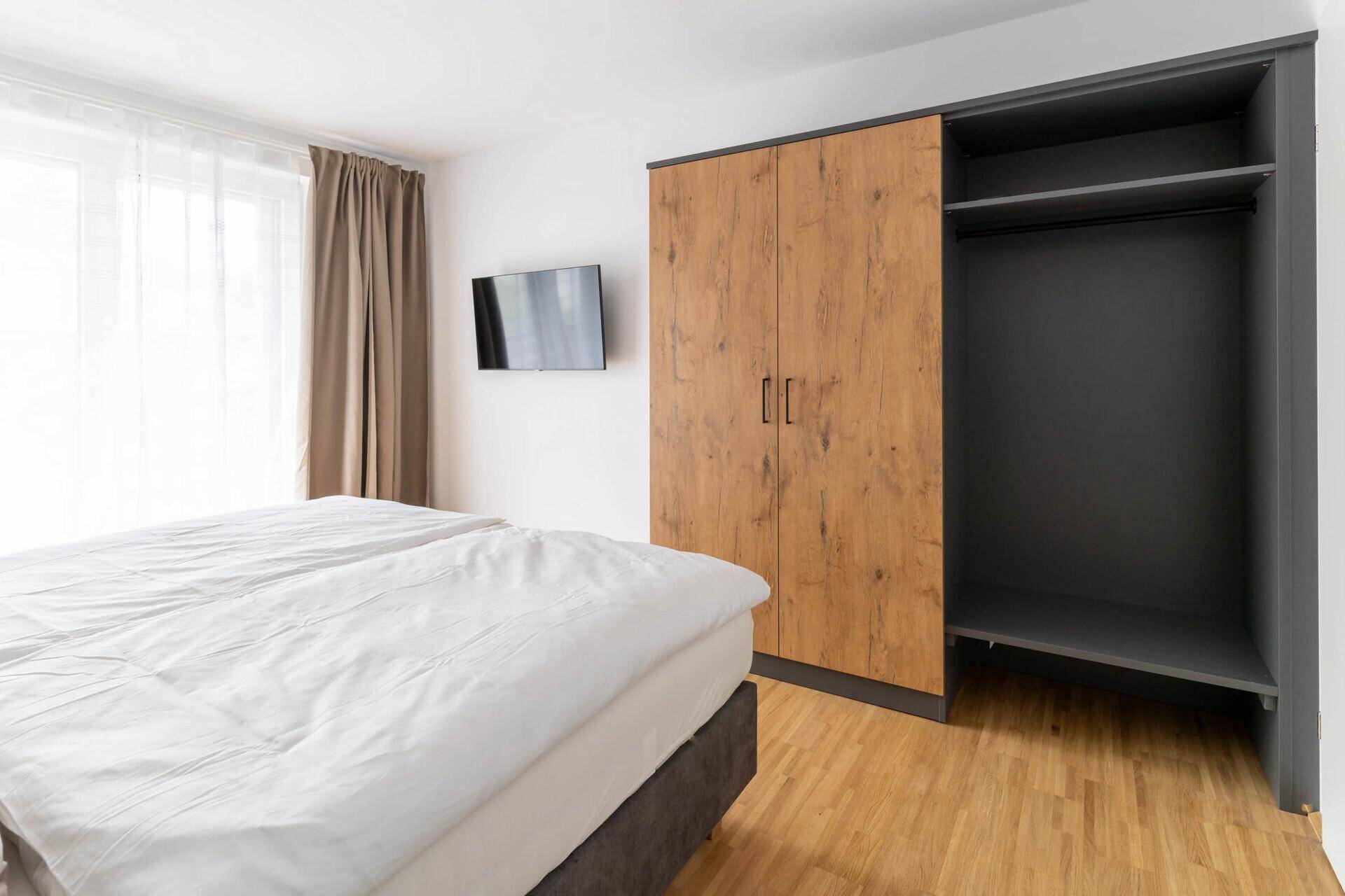 Schlafzimmer mit Doppelbett, Holzboden und einem Kleiderschrank.