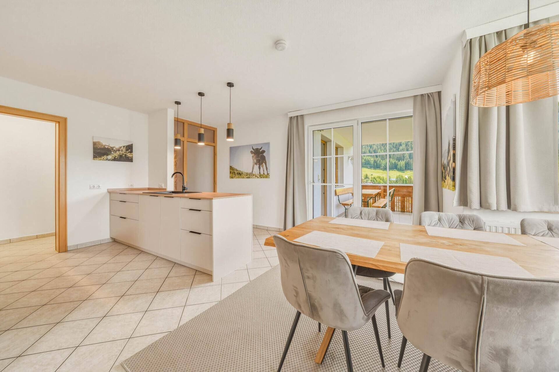 Heller Essbereich mit großem Holztisch, modernen Stühlen und Zugang zum Balkon.