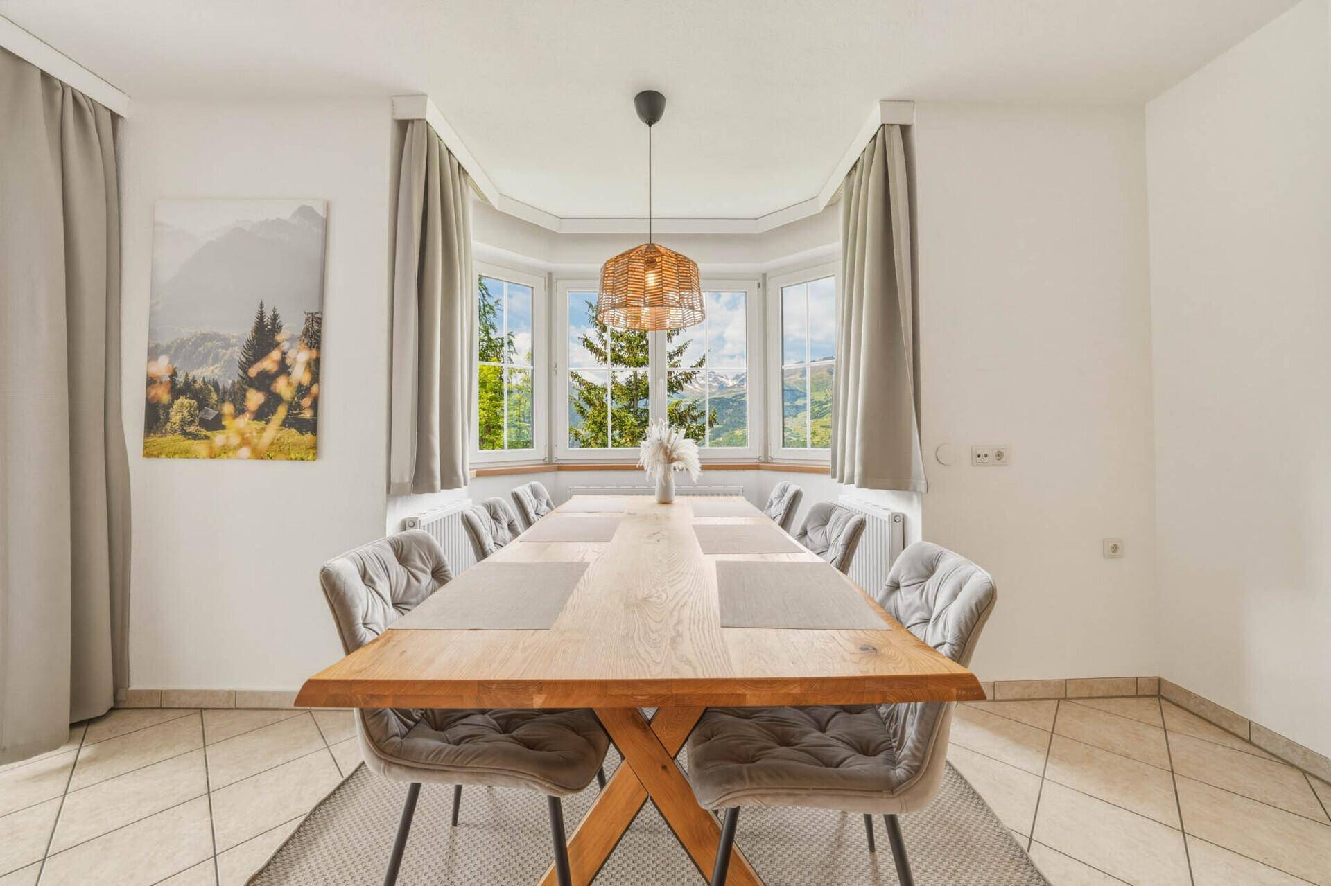 Eleganter Essbereich mit großem Holztisch und Panoramafenstern mit Bergblick.