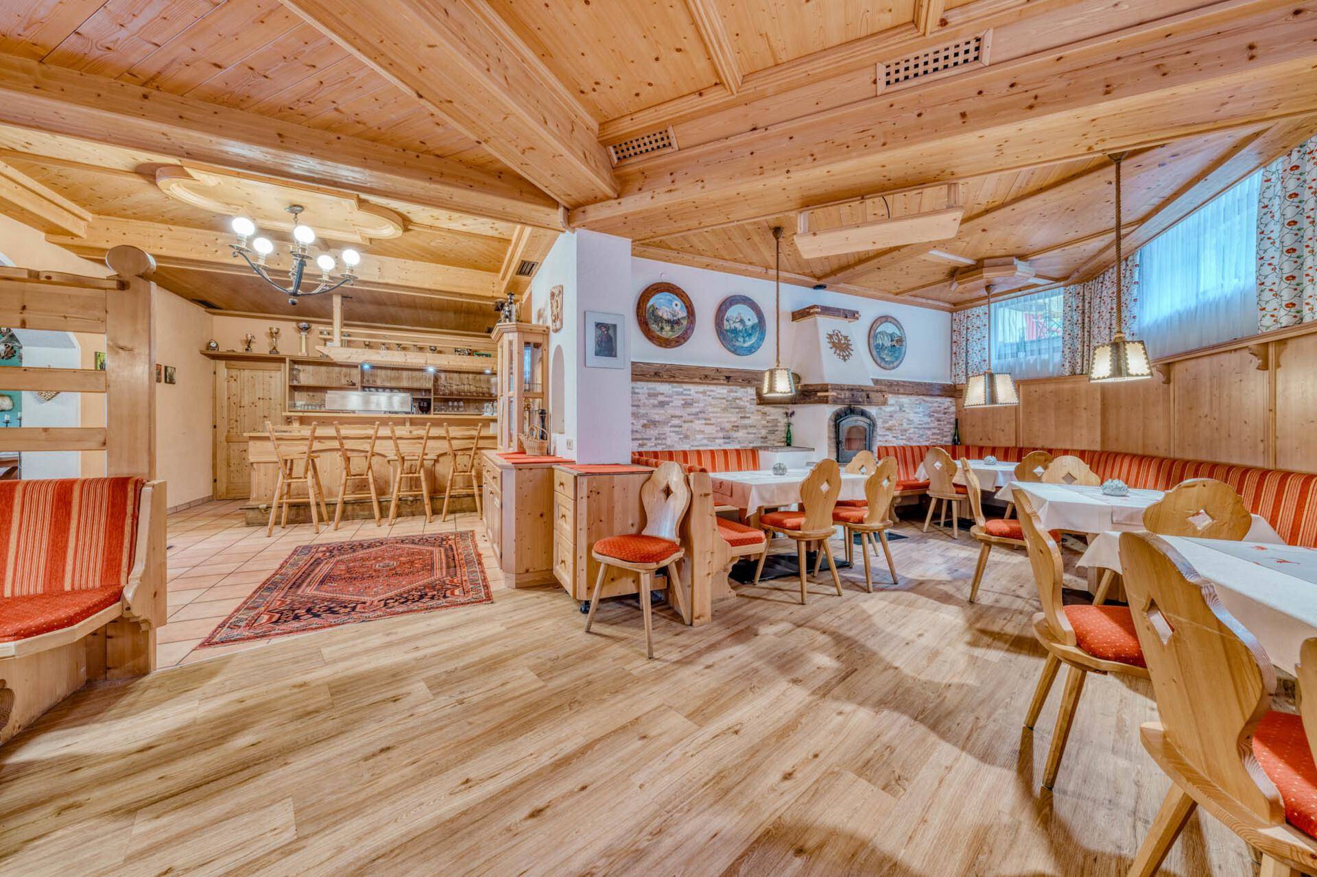 Geräumiger Speisesaal mit Holzbalkendecke, rustikalen Tischen und einem Kamin im Hintergrund.