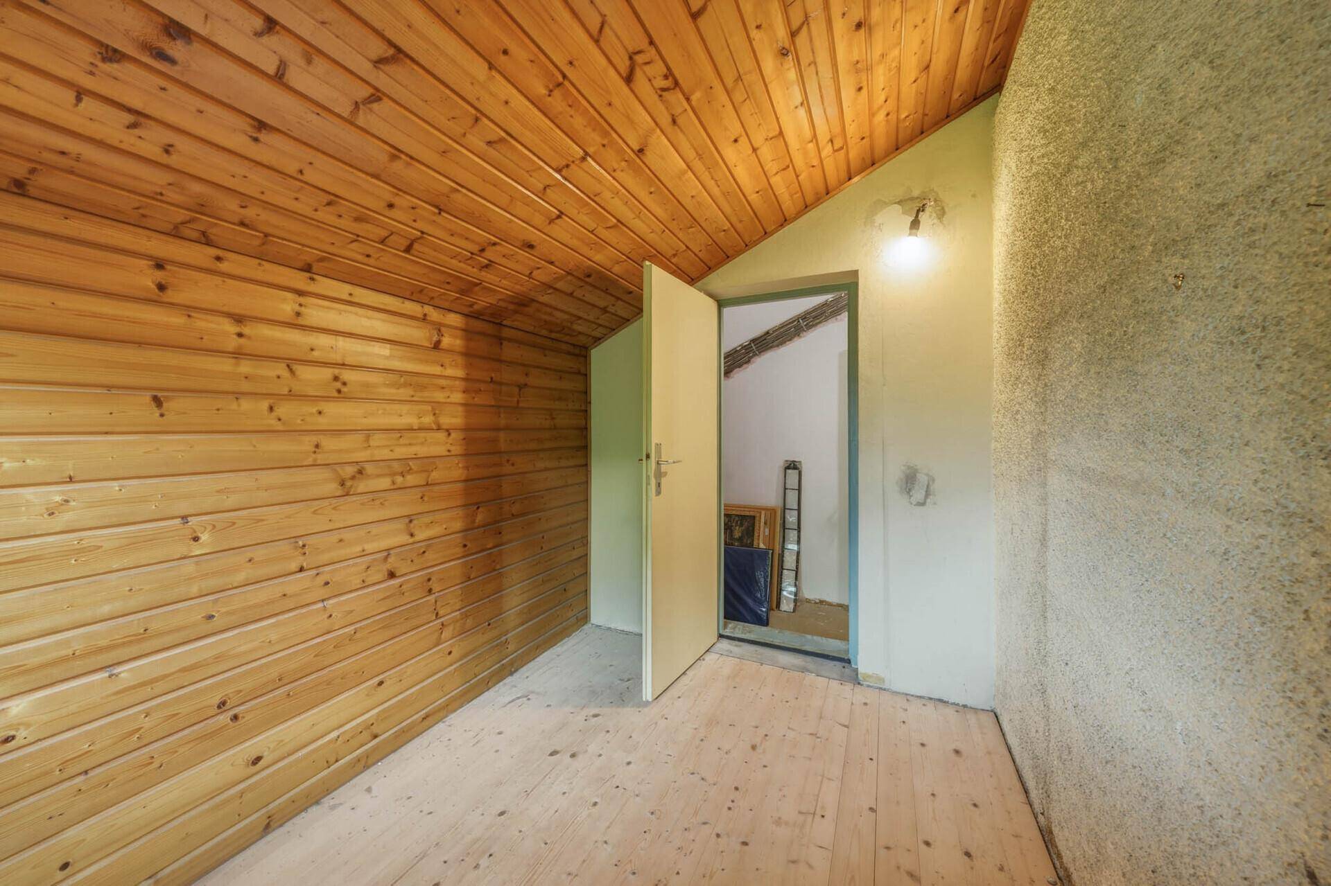 Dachbodenraum mit Holzverkleidung an Wänden und Decke, sowie einem Holzboden.