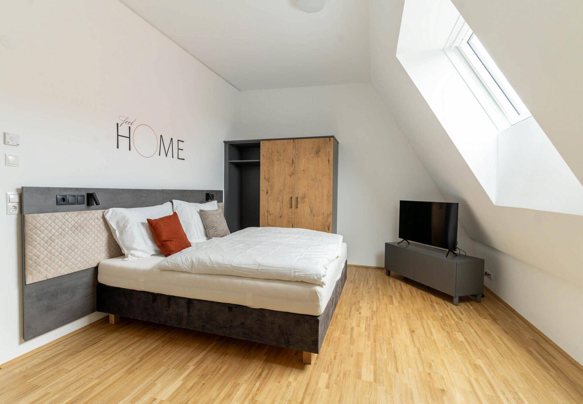 Detailansicht des Bettes mit Kissen und Wandleuchte im Schlafzimmer.