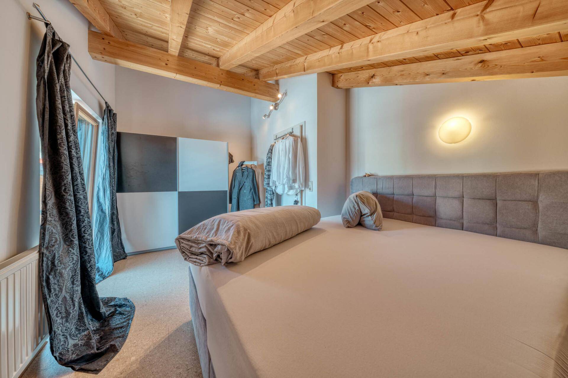 Schlafzimmer mit Holzbalkendecke, Doppelbett und gemütlicher Atmosphäre.