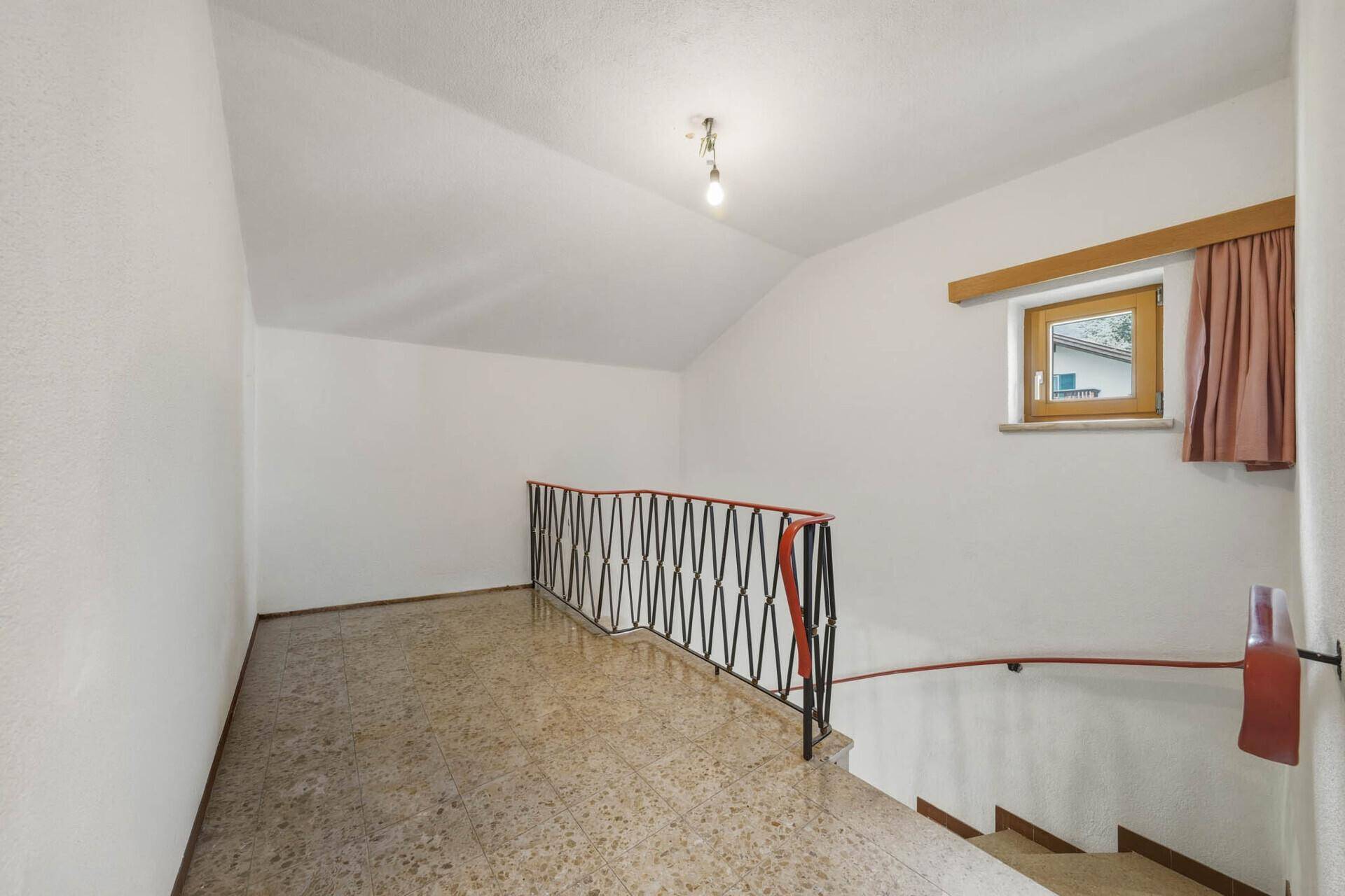 Oberer Flur mit Terrazzoboden, Geländer und Zugang zu weiteren Zimmern im Dachgeschoss.