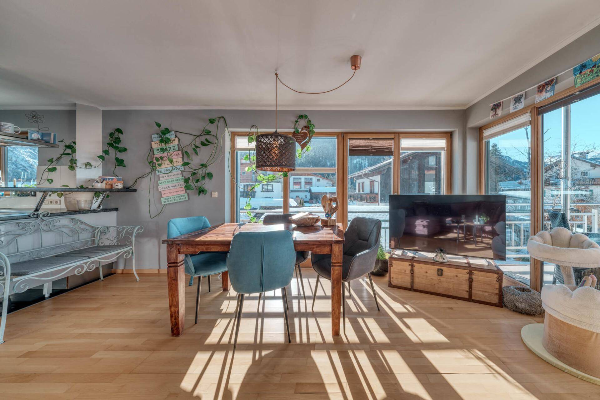 Gemütlicher Essbereich mit Holztisch, modernen Stühlen und Blick ins Grüne.