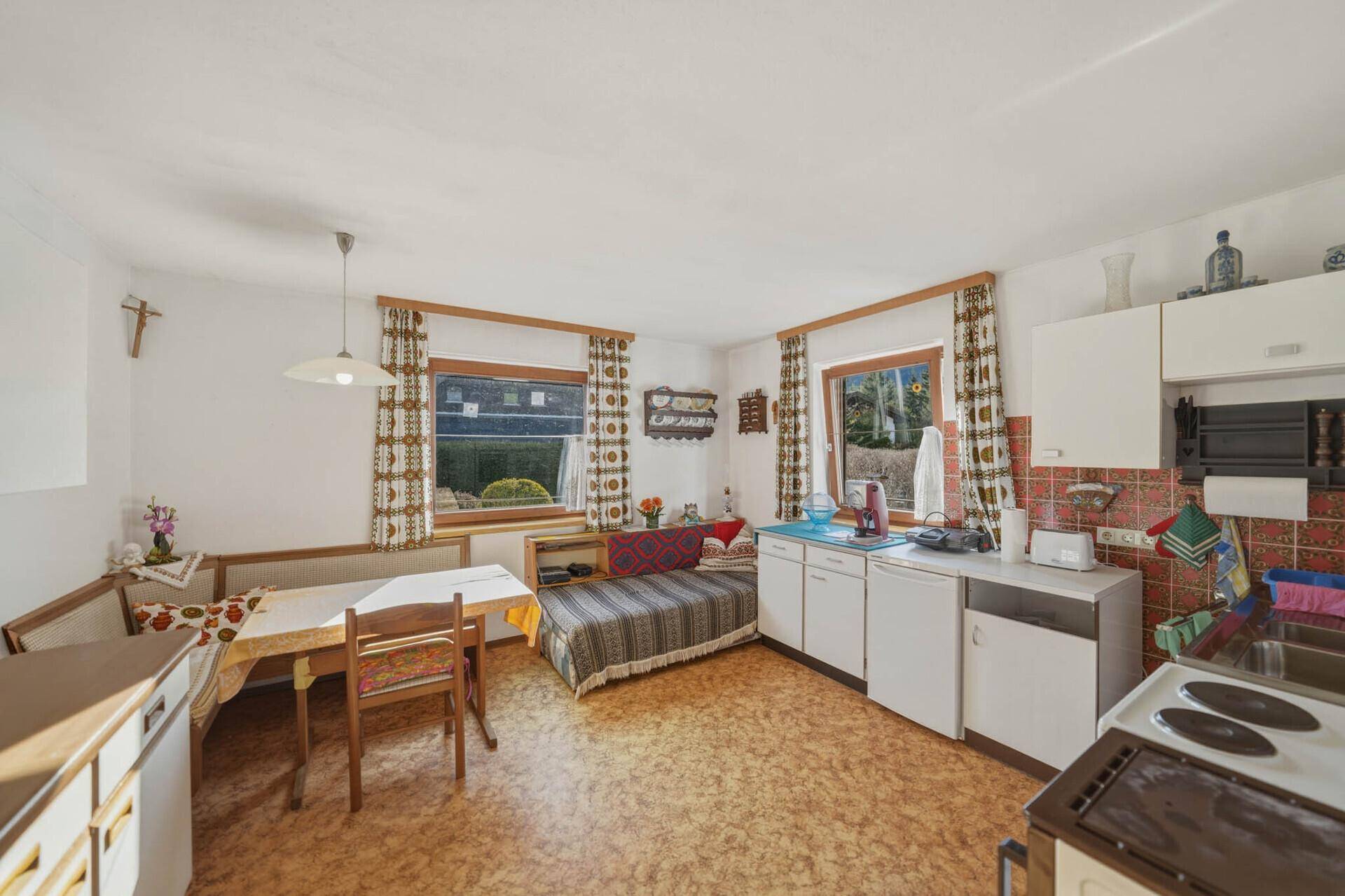Traditionelle Wohnküche mit Essecke, Schlafsofa und einfacher Ausstattung.