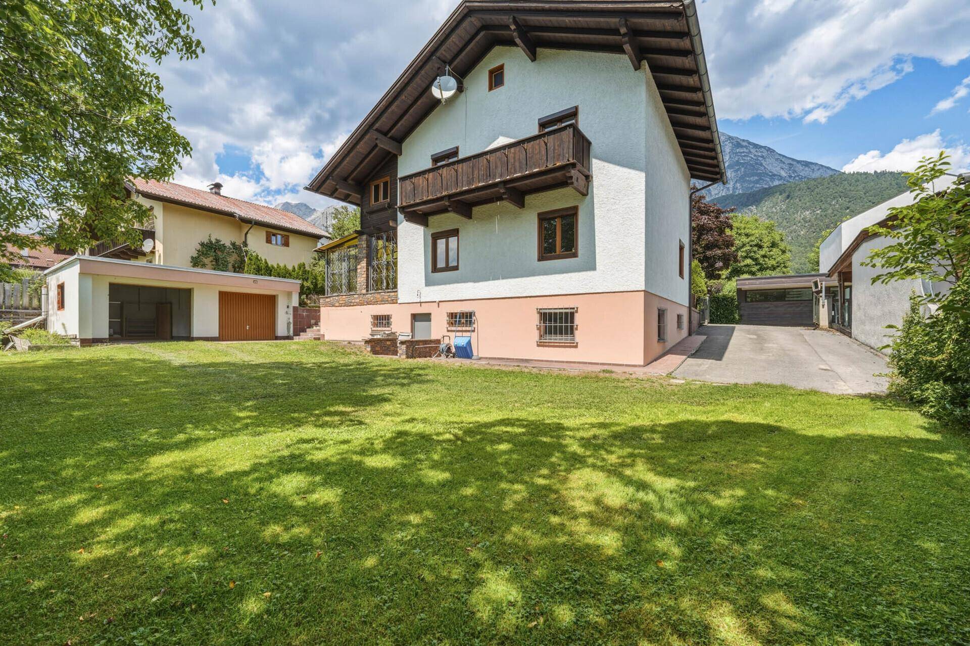 Hinteransicht des Hauses mit großem Rasen, kleinem Balkon und Bergblick.