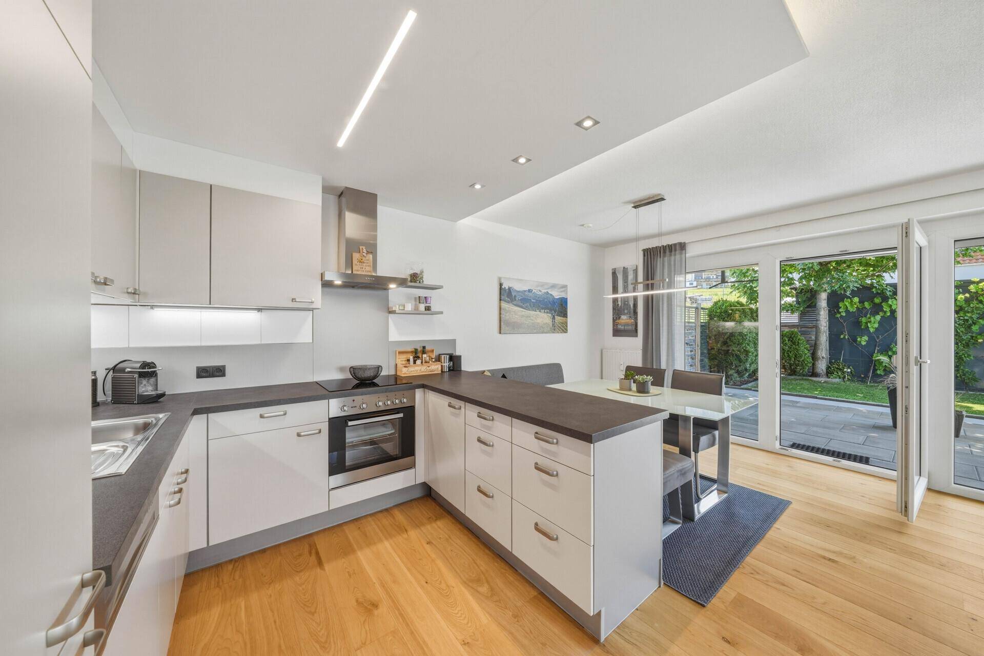 Moderne Einbauküche mit Essbereich, dunkler Arbeitsplatte und Zugang zur Terrasse.