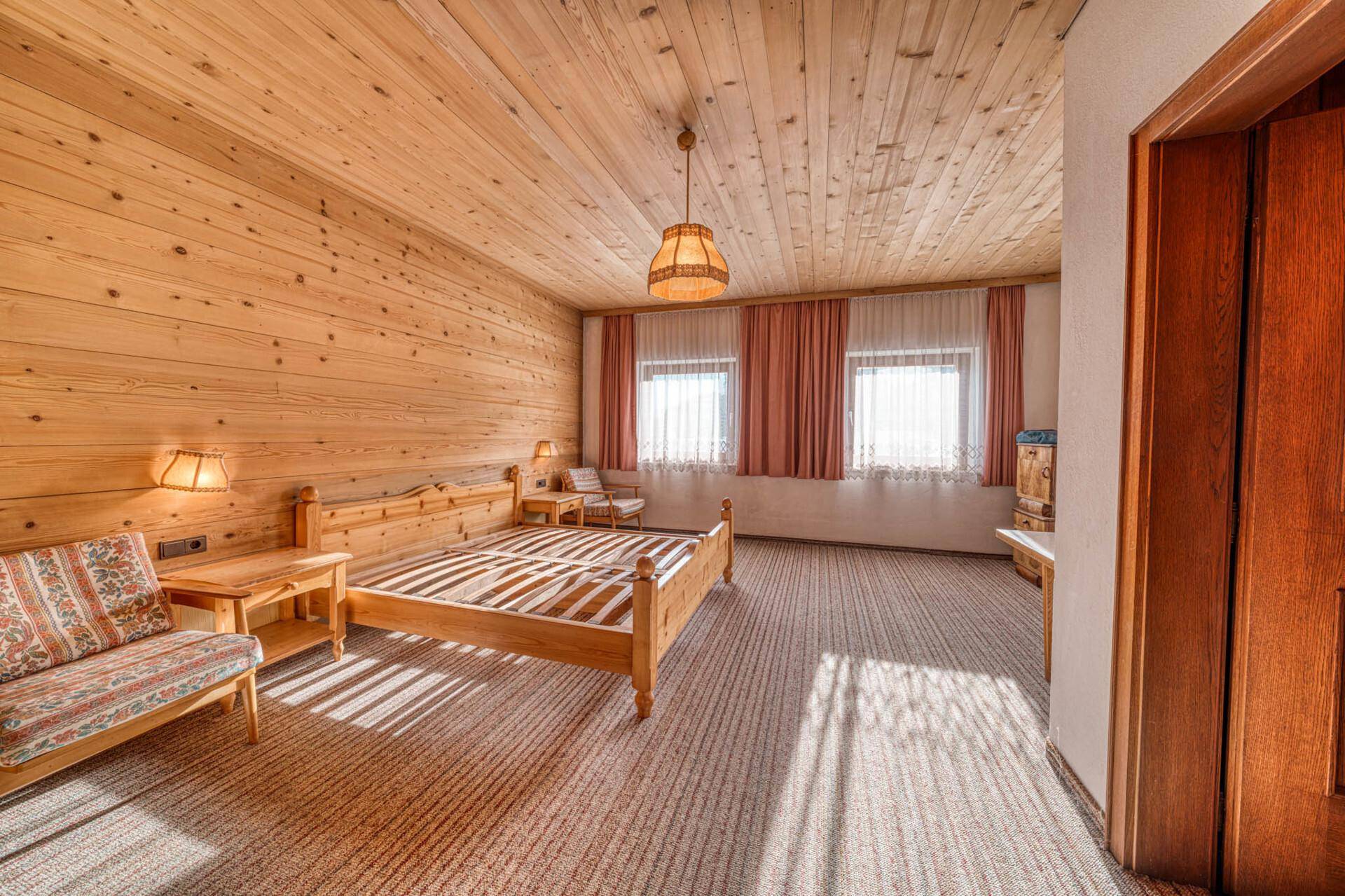 Gemütliches Schlafzimmer im alpinen Stil mit Holzvertäfelung, Teppichboden und zwei Einzelbetten.