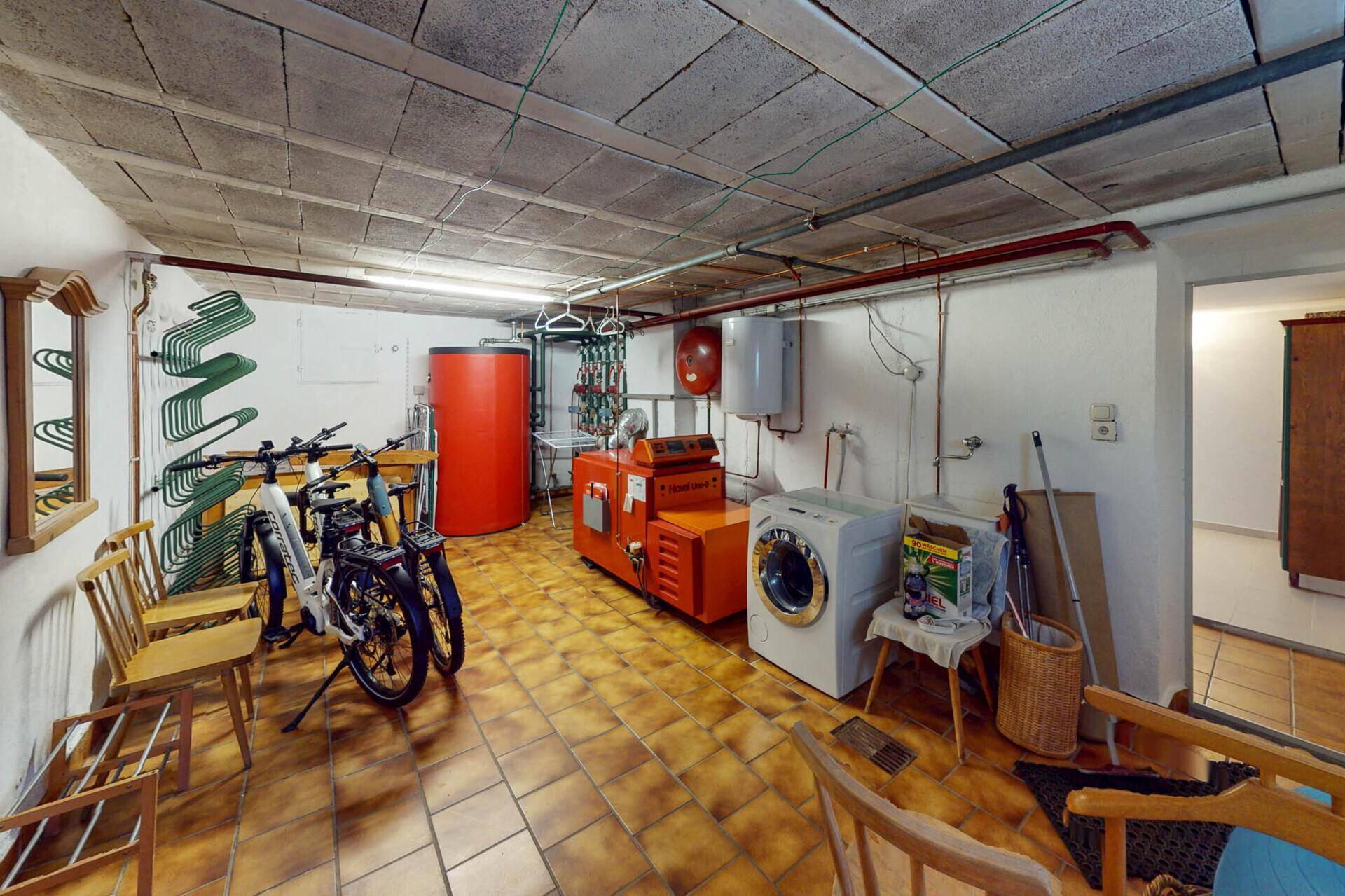 Geräumiger Kellerraum mit Heizungsanlage, Waschmaschine und Fahrrädern.
