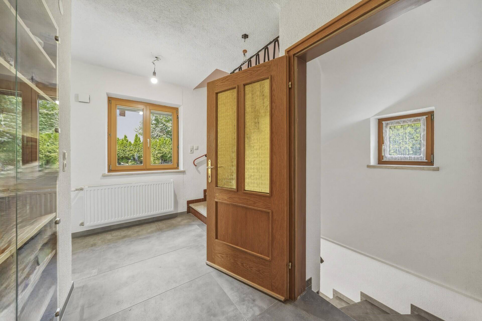 Eingangsbereich mit Holztür, Fenster und Treppenaufgang, der zu den oberen Etagen führt.