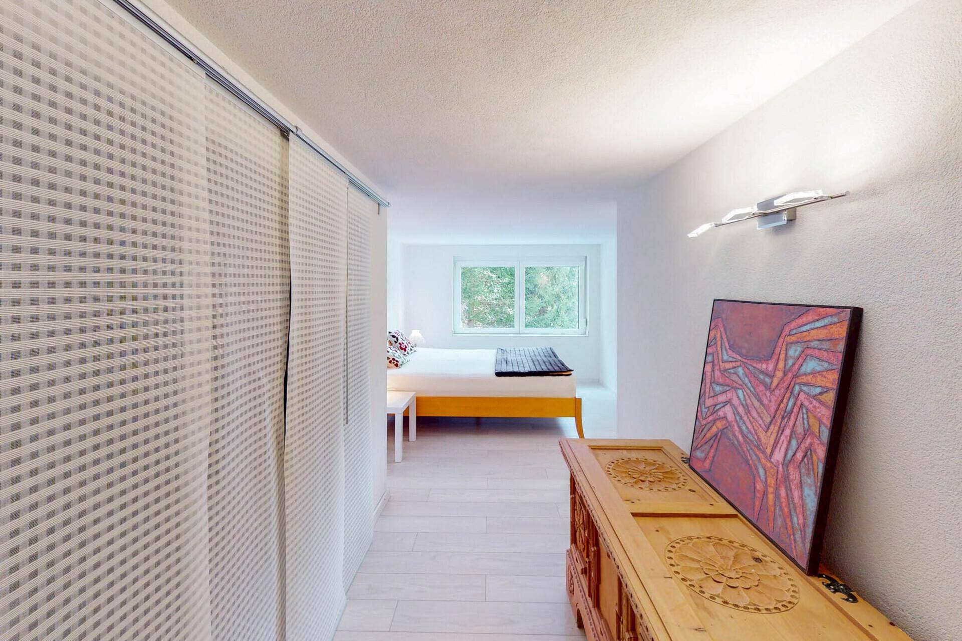 Geräumiges Schlafzimmer mit Parkettboden und Blick ins Grüne.