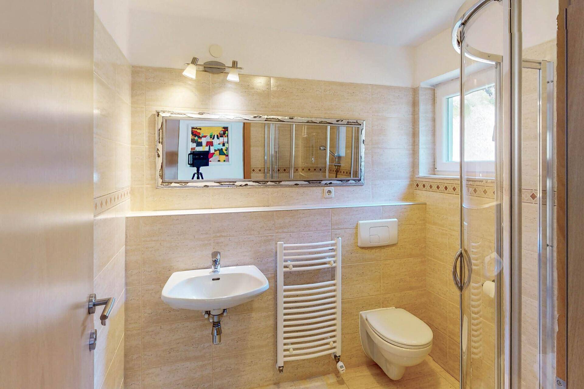 Modernes Badezimmer mit Duschkabine, WC, Waschbecken und beheiztem Handtuchhalter.
