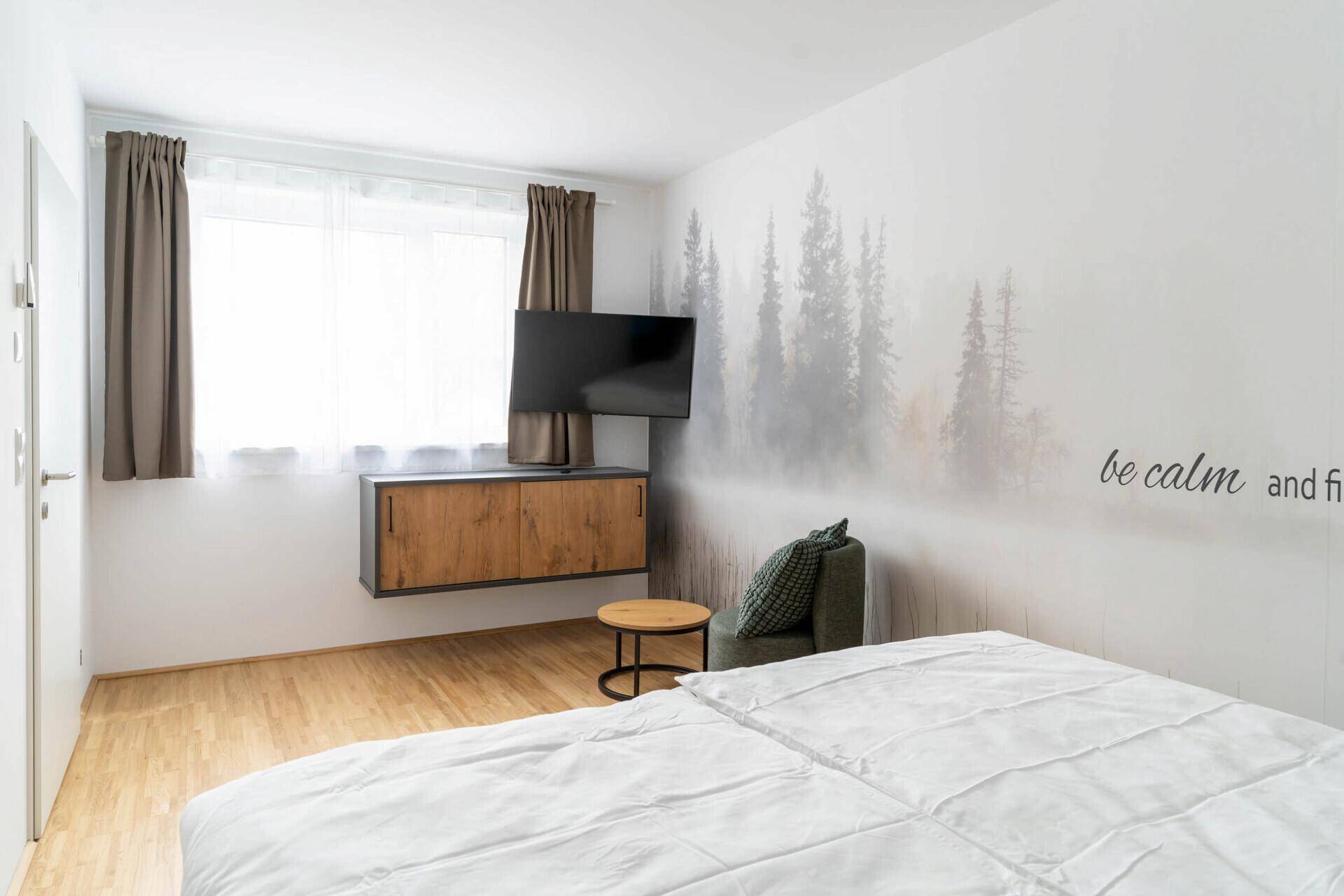 Helles Schlafzimmer mit Doppelbett, Holzboden und dekorativer Wandgestaltung.