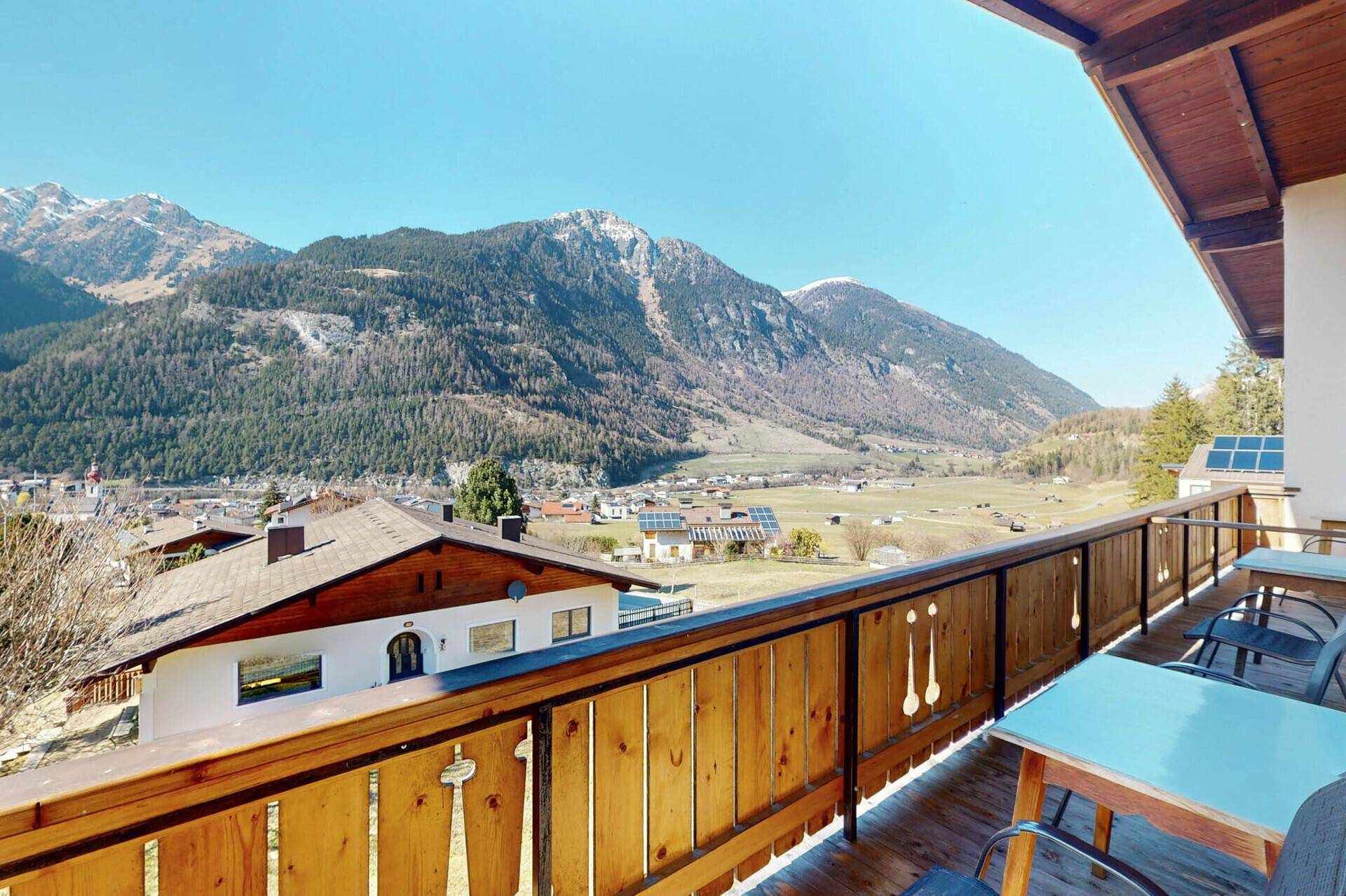 Geräumiger Balkon mit Sitzgelegenheiten und weitem Blick auf die Berge und das Tal.
