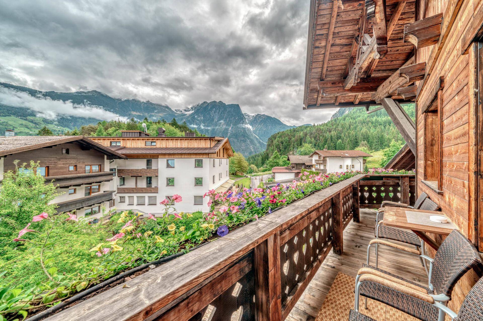 Blühender Balkon mit Sitzgelegenheiten und beeindruckendem Blick auf die Berge.