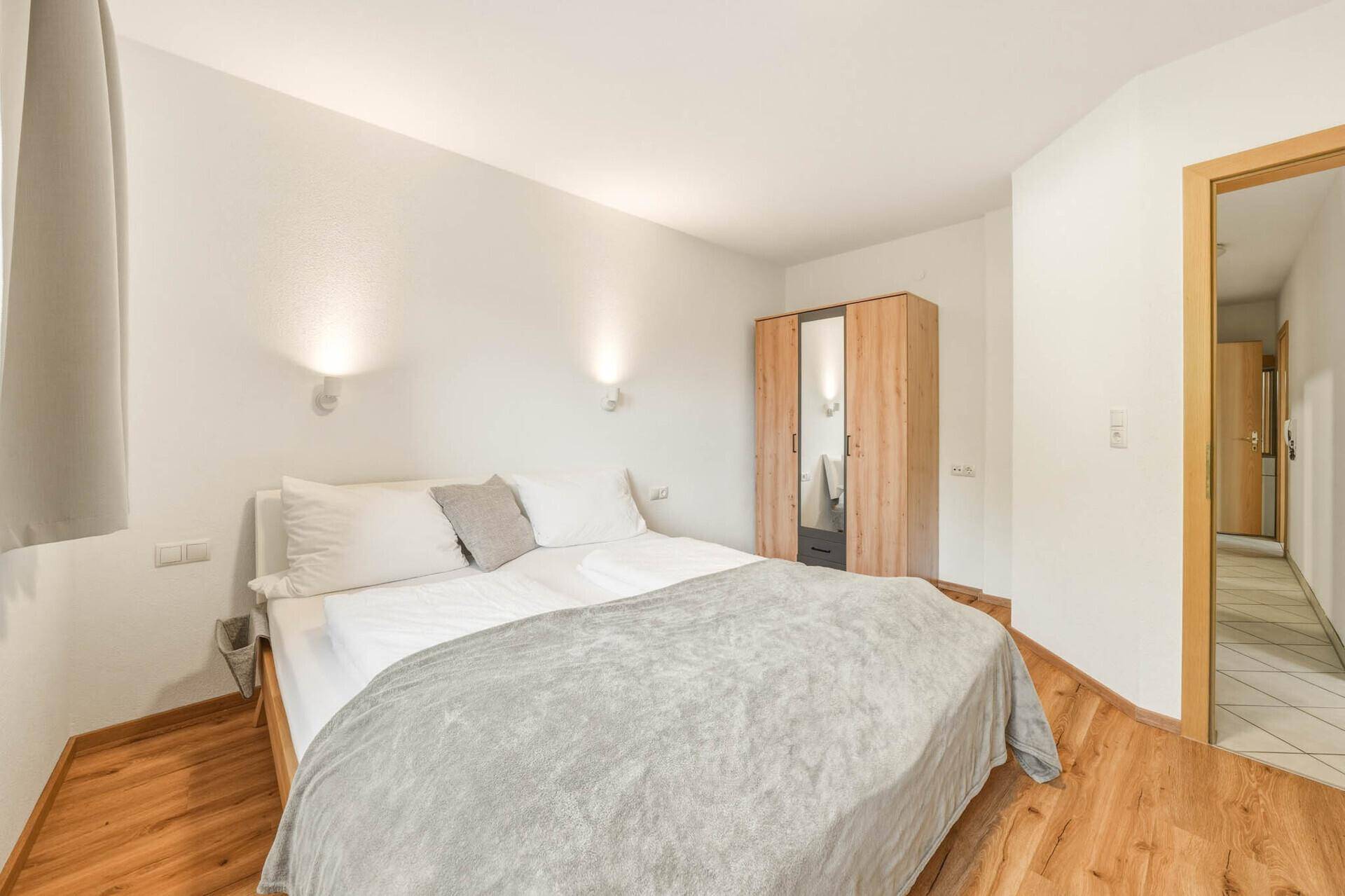 Gemütliches Schlafzimmer mit Doppelbett, Holzschrank und Blick in den angrenzenden Flur.