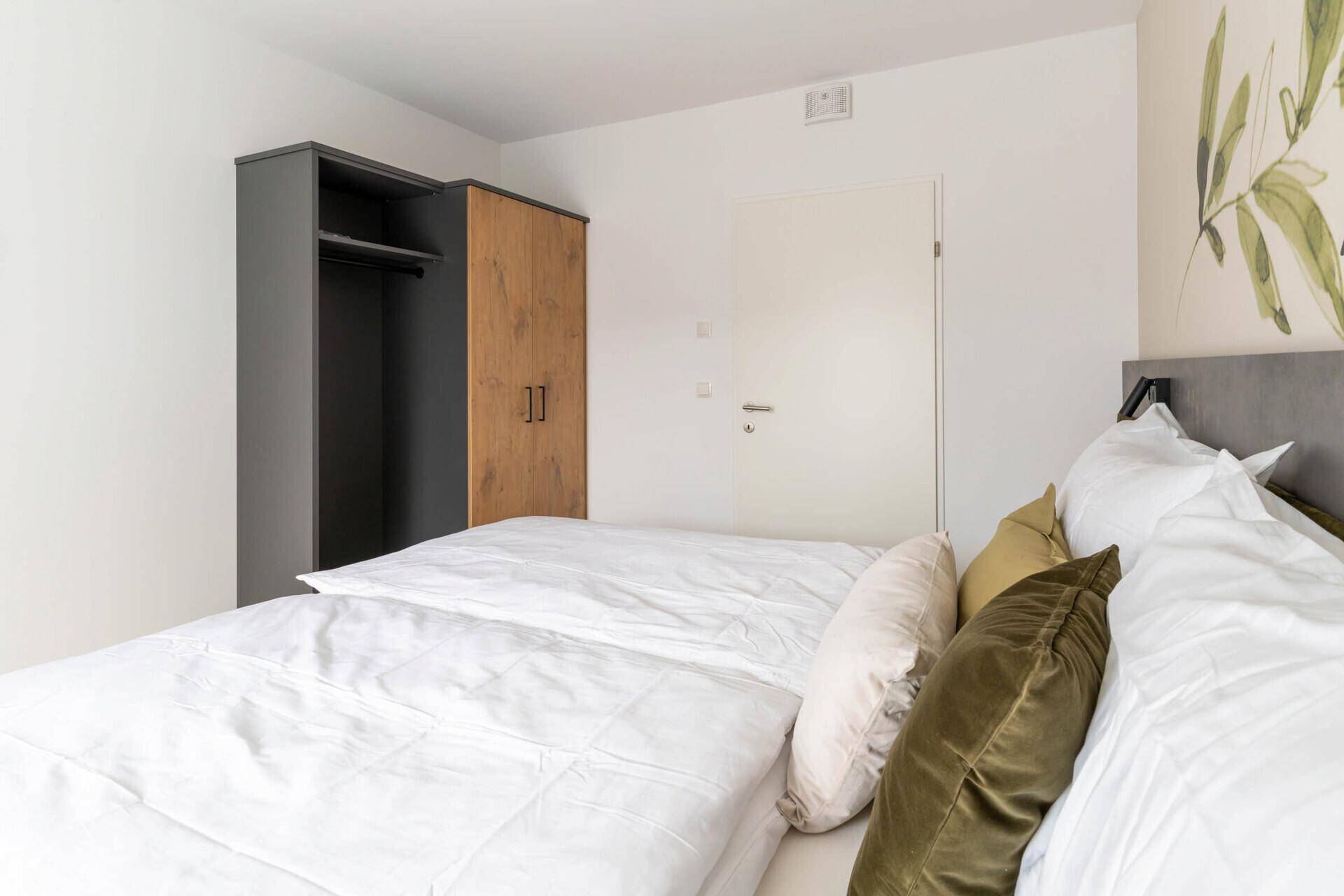 Schlafzimmer mit zwei Einzelbetten, Holzboden und einem Kleiderschrank.