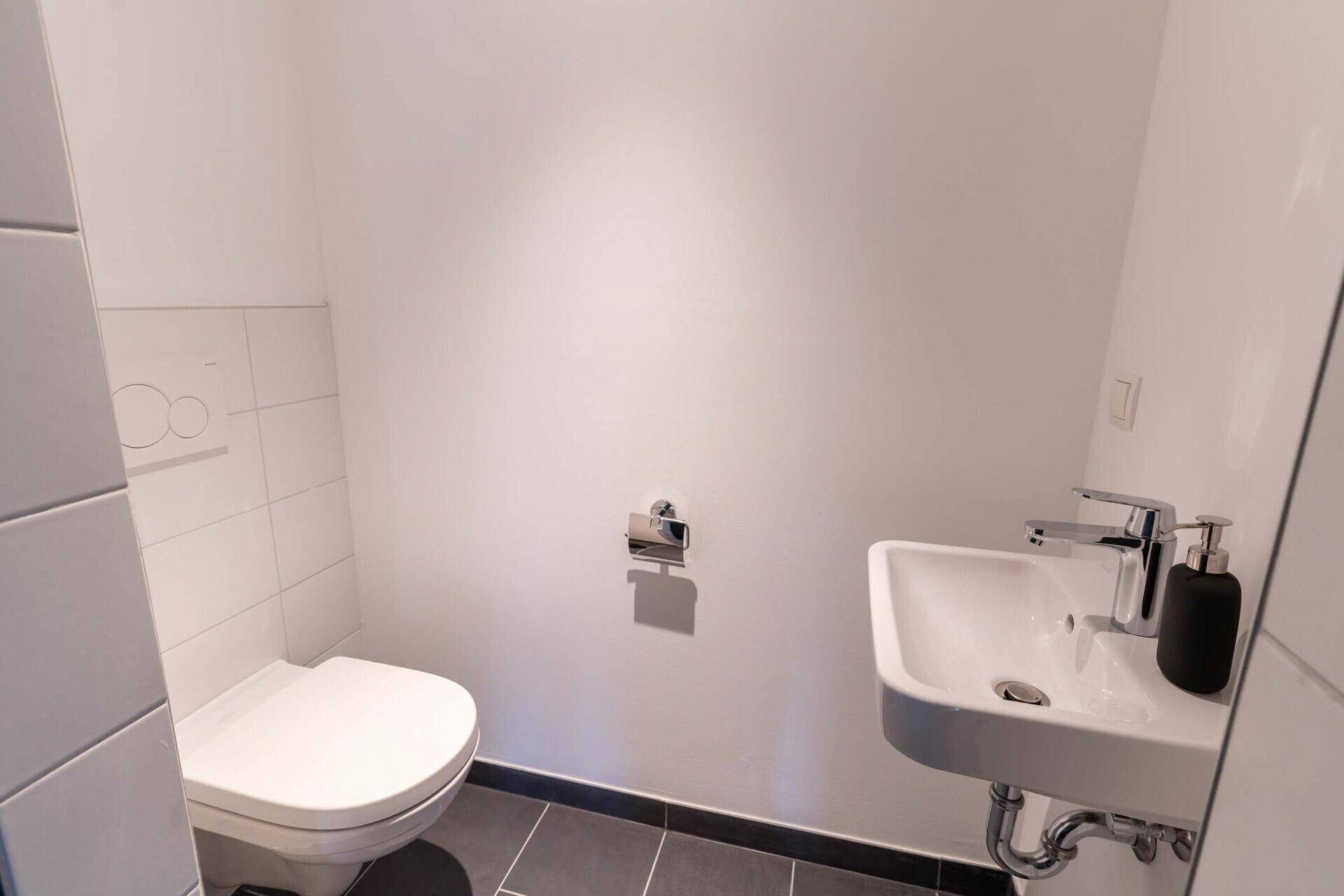 Modernes Gäste-WC mit Wand-WC und kleinem Waschbecken.