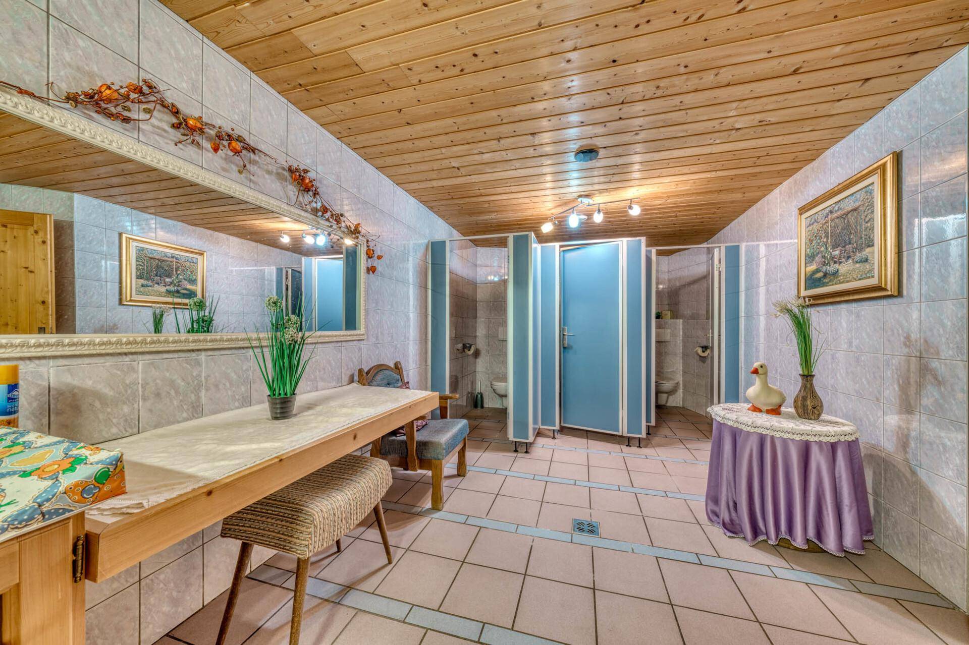 Geräumiger Toilettenbereich mit mehreren Waschbecken, Spiegeln und Holzbalkendecke.