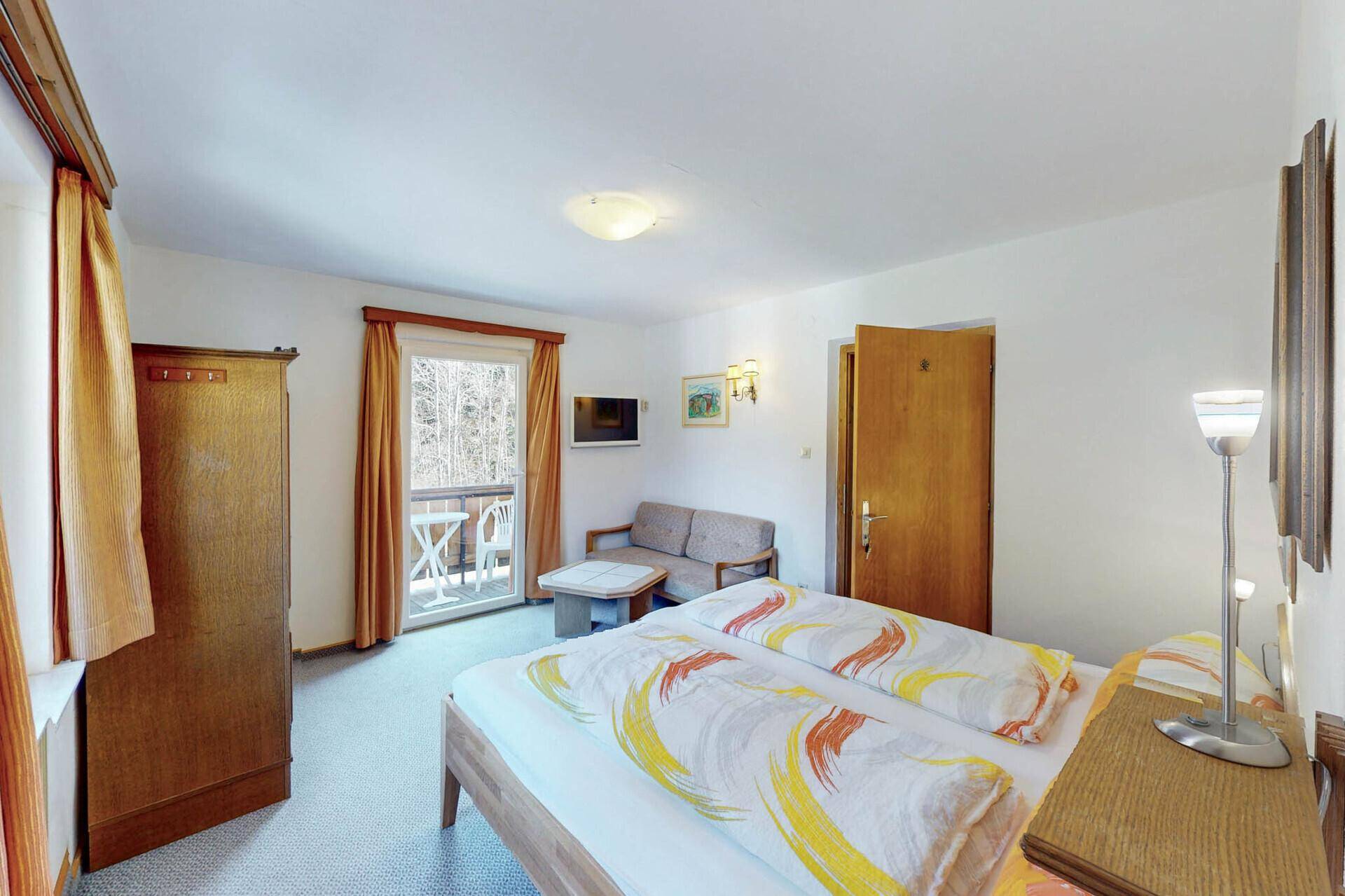 Helles Schlafzimmer mit Doppelbett, Teppichboden und Balkonzugang.