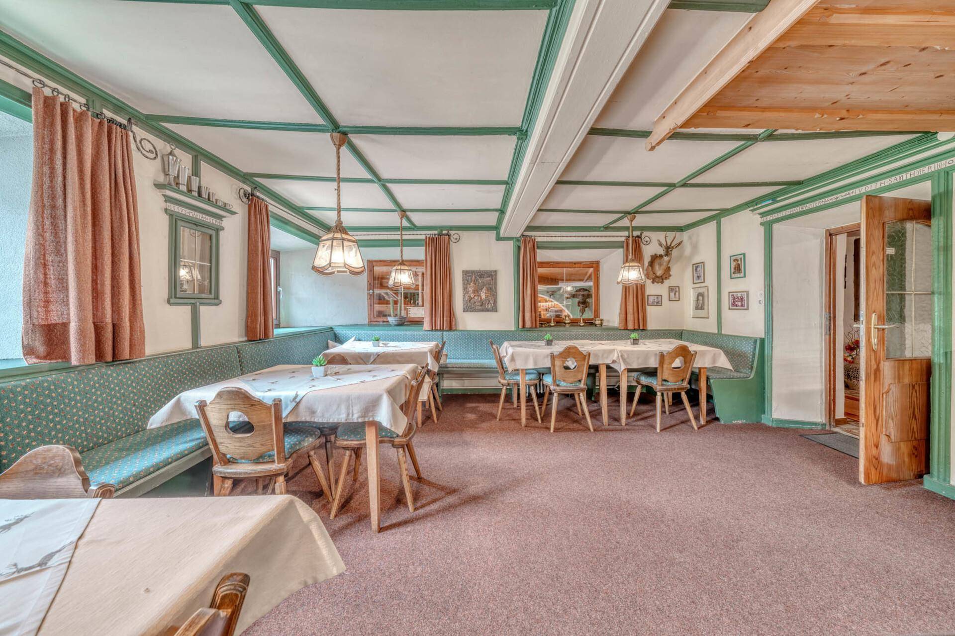 Geräumiger Speisesaal mit grünen Akzenten, Holztischen und traditioneller Einrichtung.