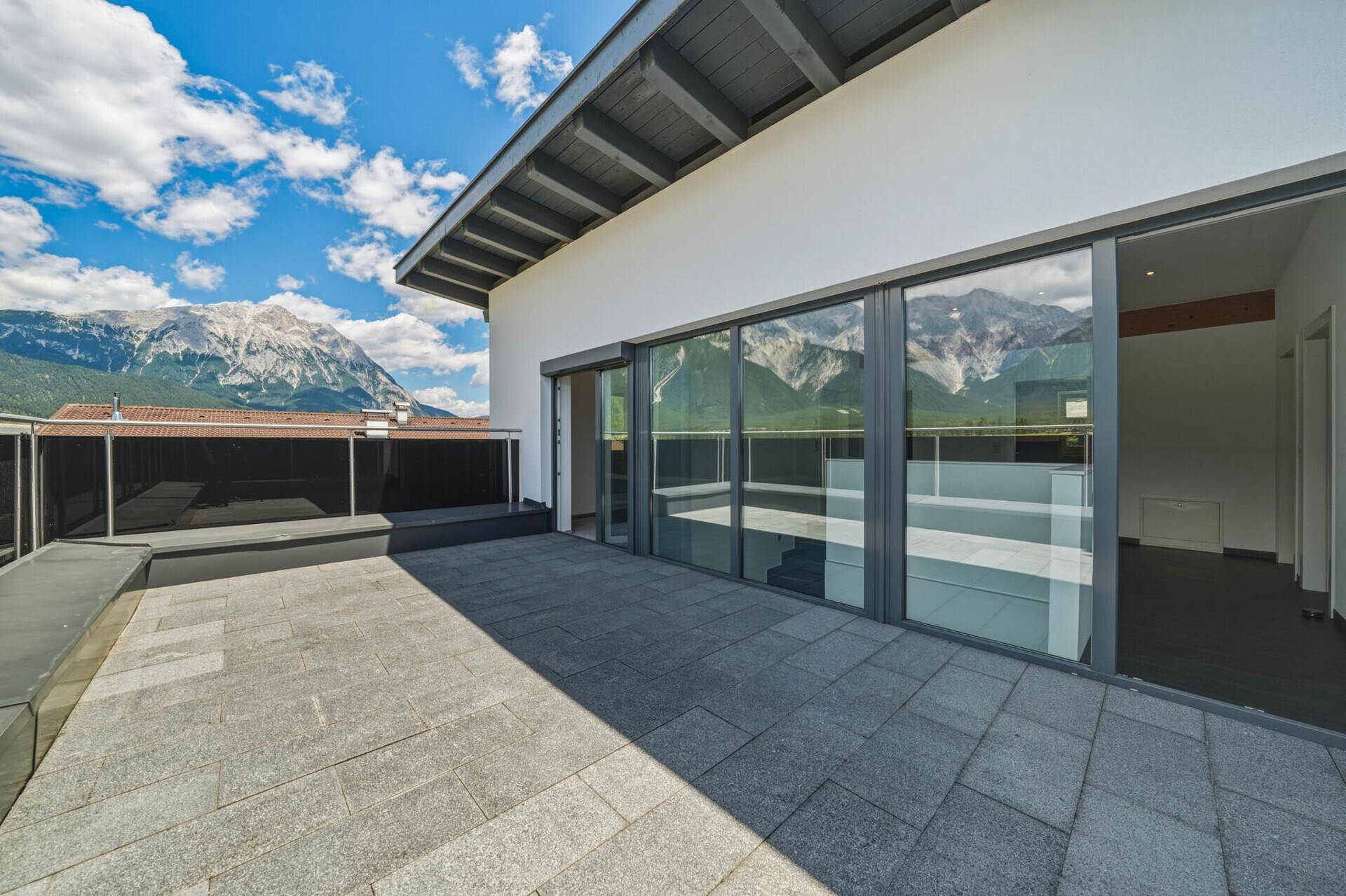 Geräumige Dachterrasse mit Zugang zu Innenräumen und weitem Blick auf die Berge.