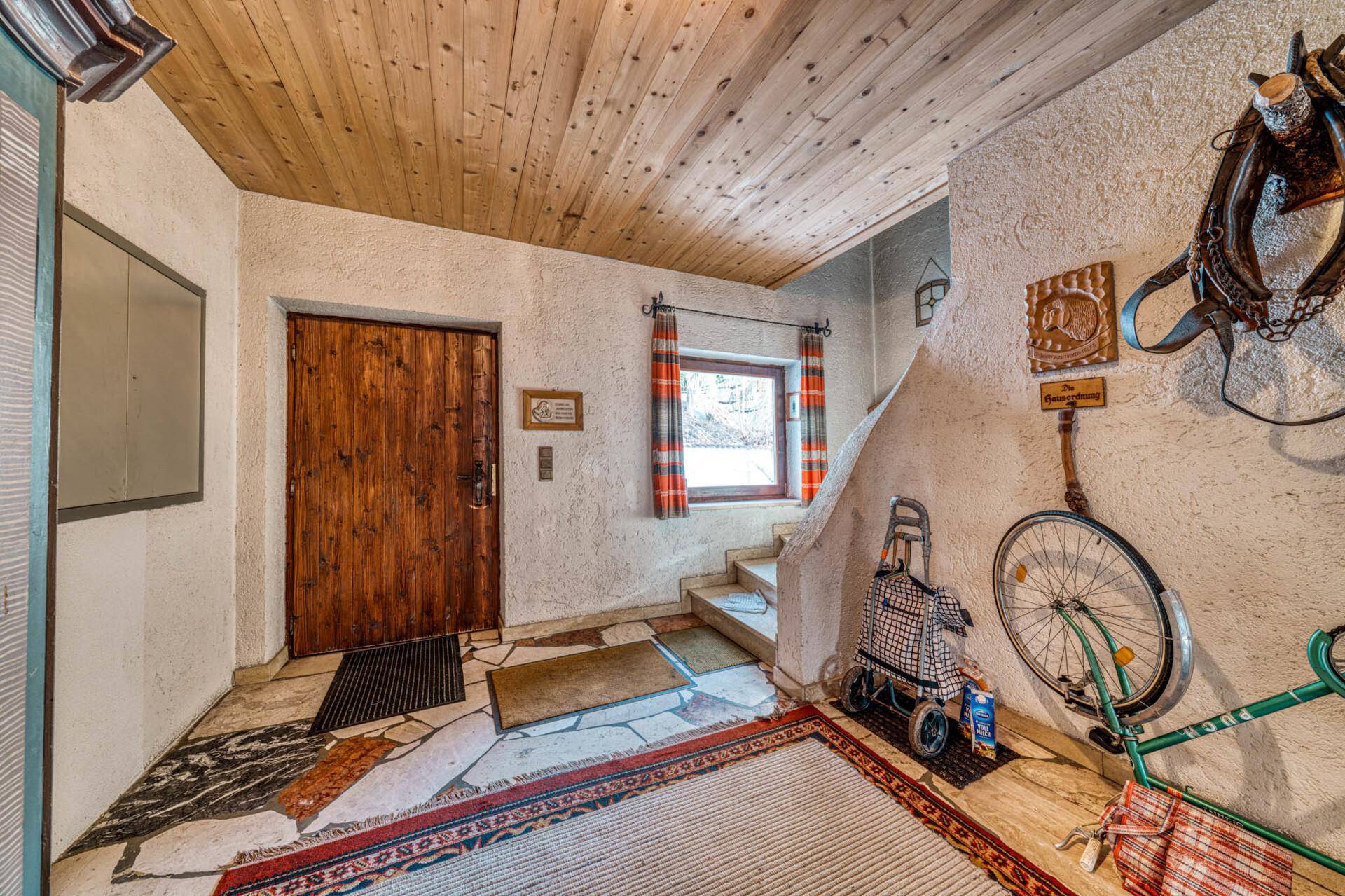 Eingangsbereich mit rustikalem Charme, Holzdecke und Treppe zum Obergeschoss.