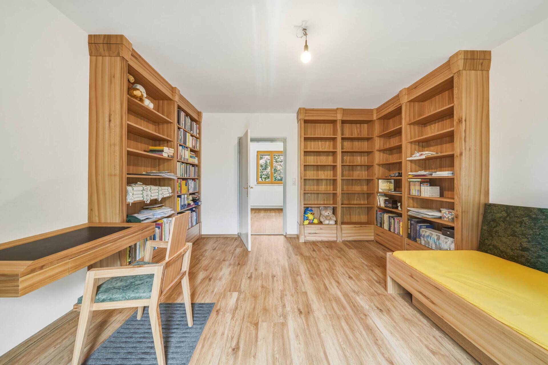 Geräumiges Arbeitszimmer mit umfangreichen Holzbücherregalen und Zugang zu einem weiteren Raum.