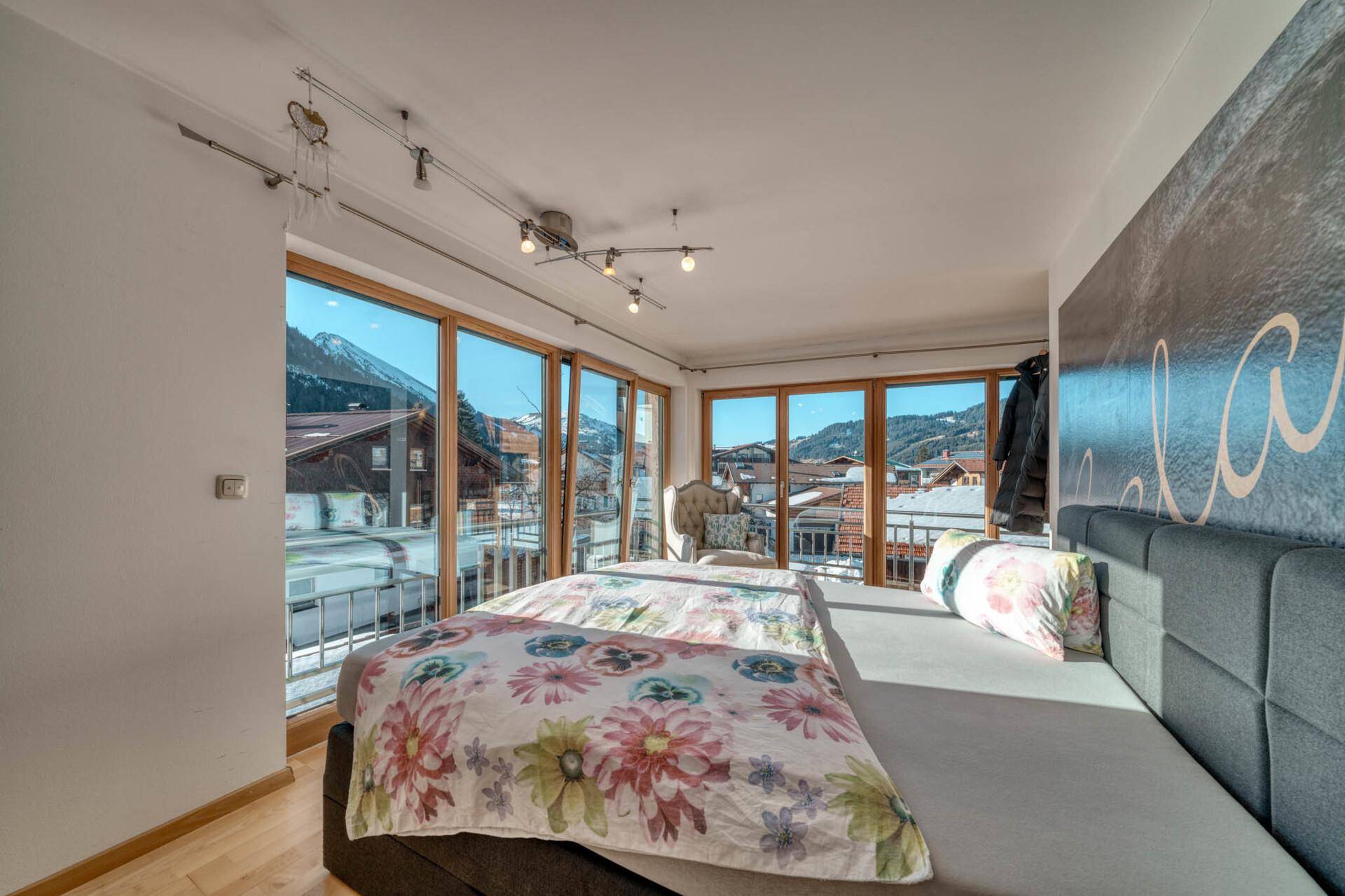 Schlafzimmer mit großen Fenstern, Doppelbett und beeindruckendem Bergblick.