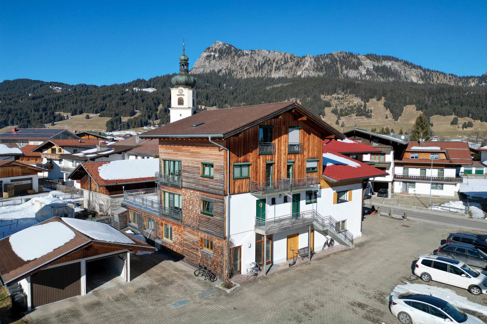 Attraktives Mehrfamilienhaus in alpiner Umgebung mit Bergblick und Parkplätzen.