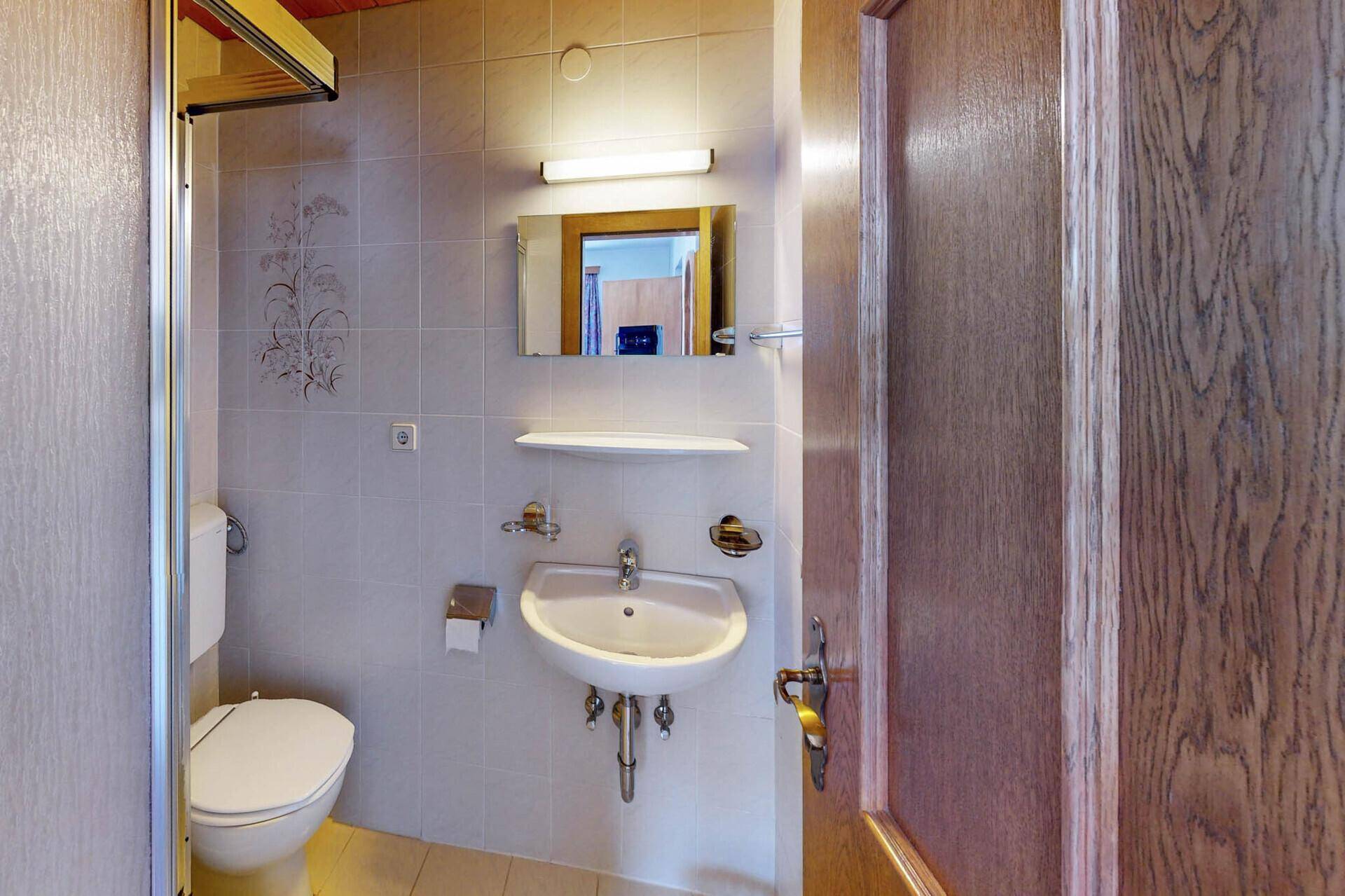 Kleines Badezimmer mit WC, Waschbecken und Duschkabine.