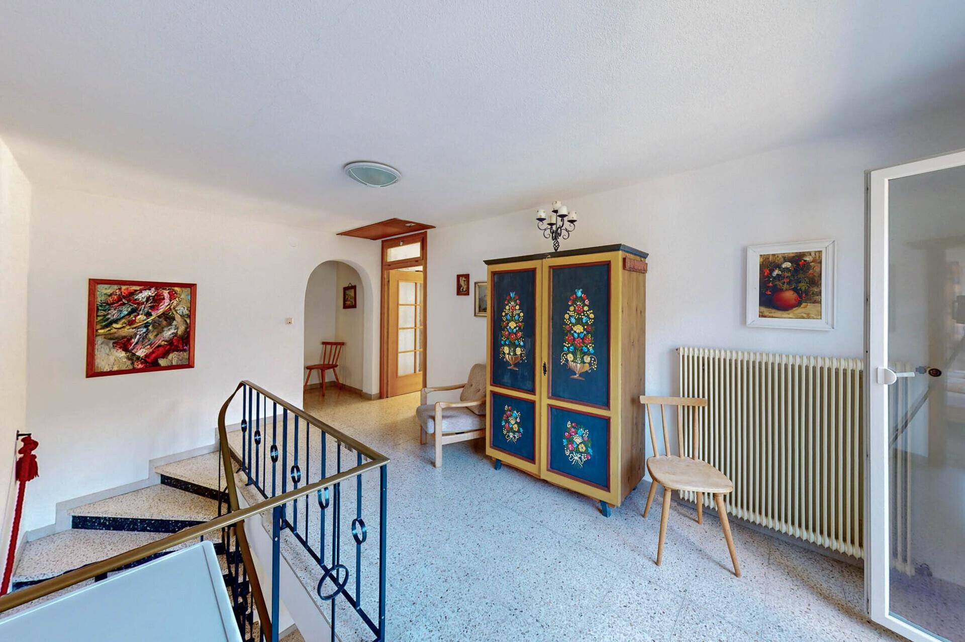 Geräumiger Flur mit Treppe, Terrazzoboden und traditionellem Schrank.