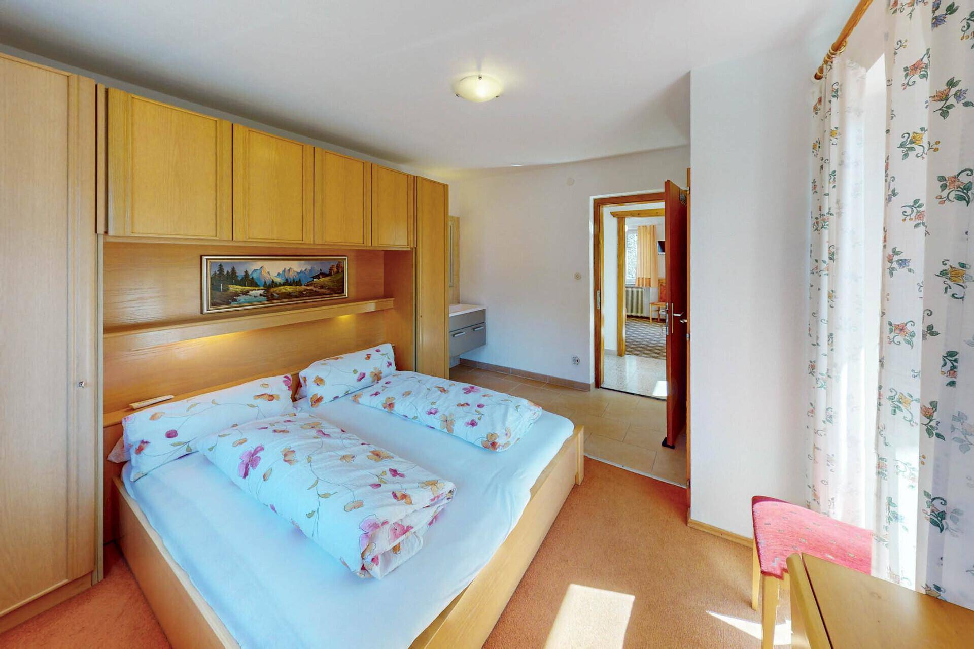 Schlafzimmer mit Doppelbett, Einbauschränken und Blick auf die Berge.