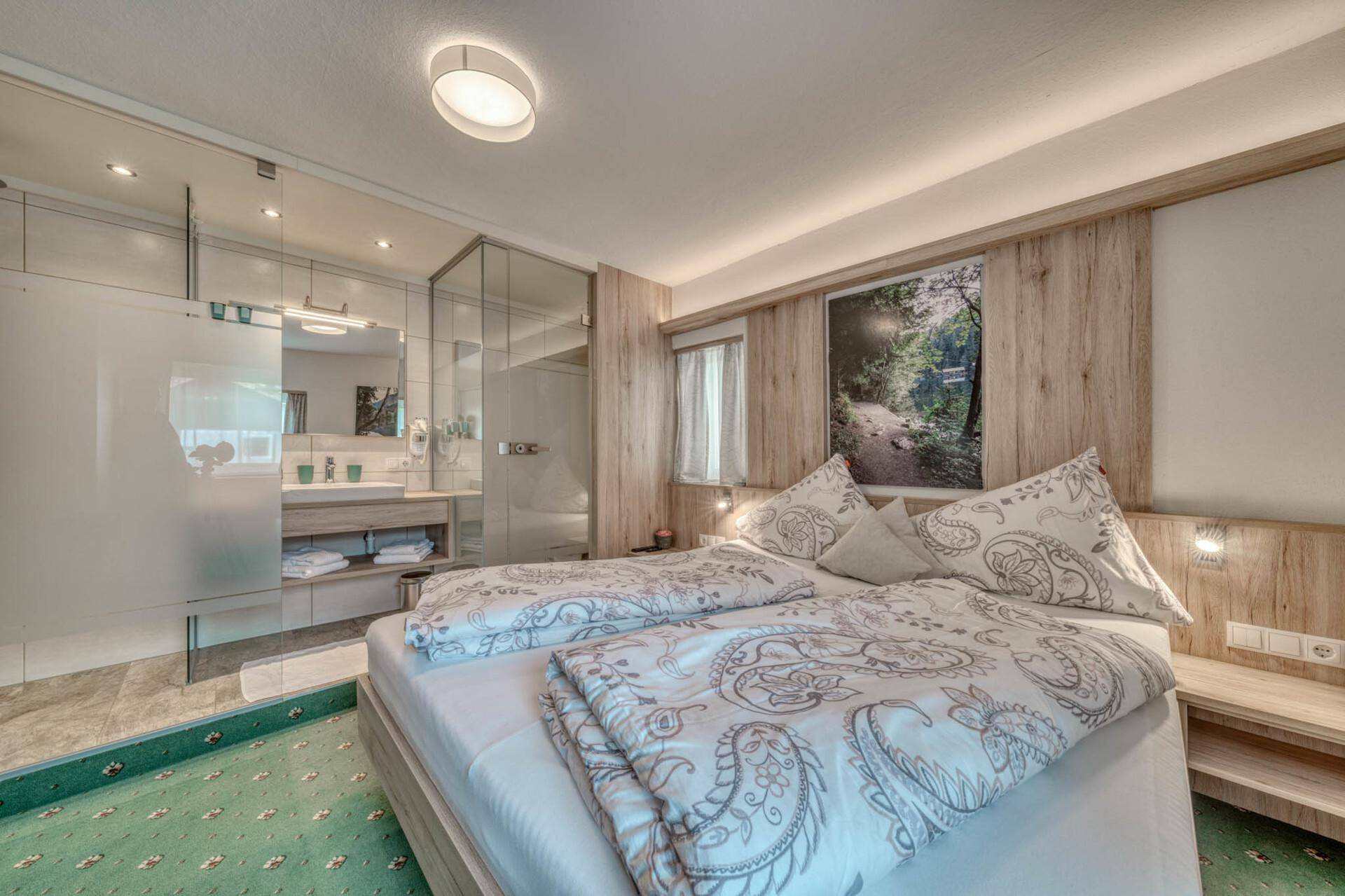 Schlafzimmer mit Doppelbett und integriertem Badezimmer, modernes Design und helle Atmosphäre.