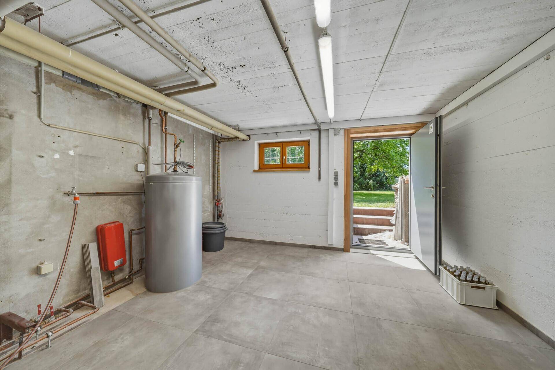 Heizungsraum im Keller mit Heizungsanlage, Warmwasserspeicher und direktem Gartenzugang.