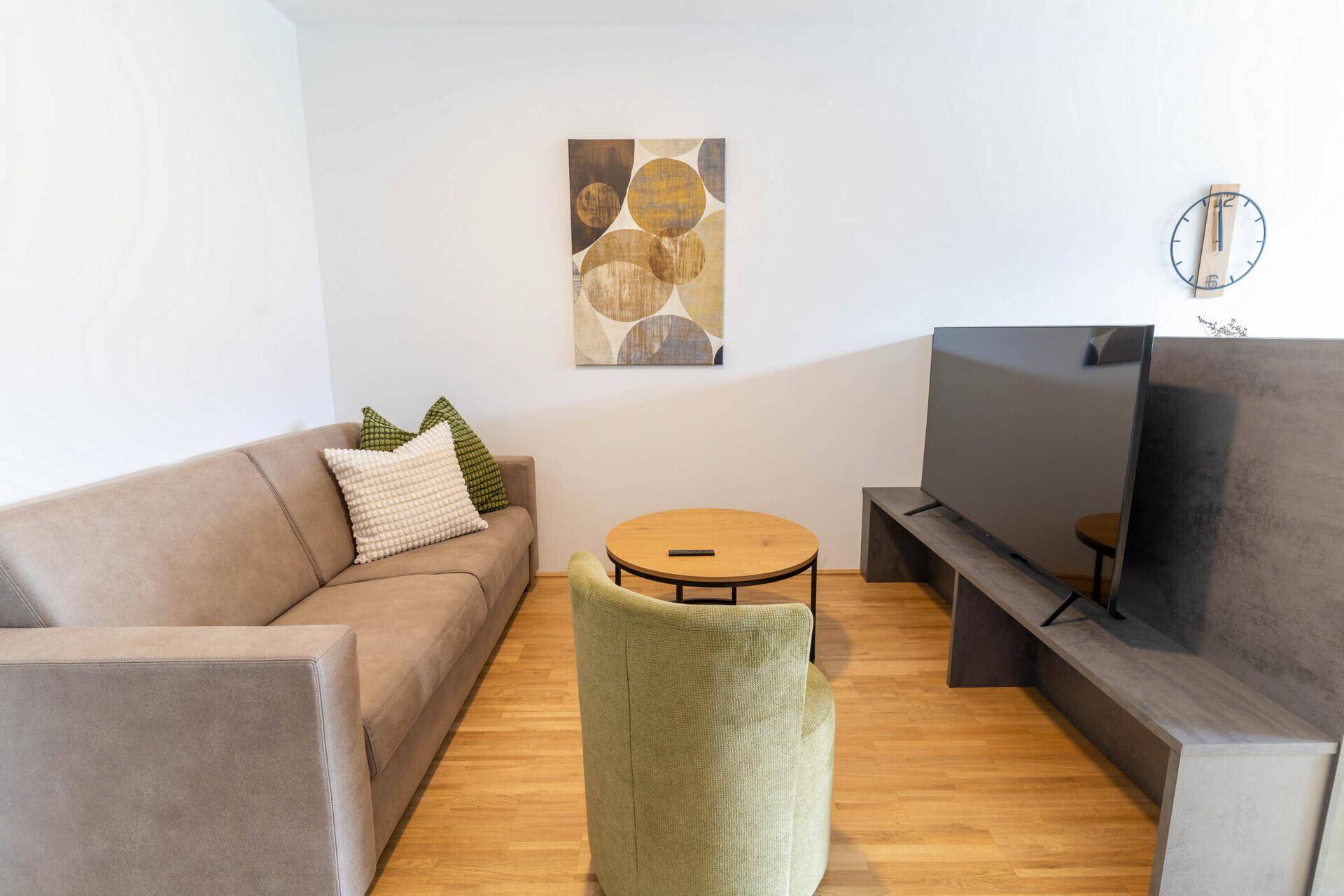 Gemütliches Wohnzimmer mit Sofa, Couchtisch und Wandfernseher.