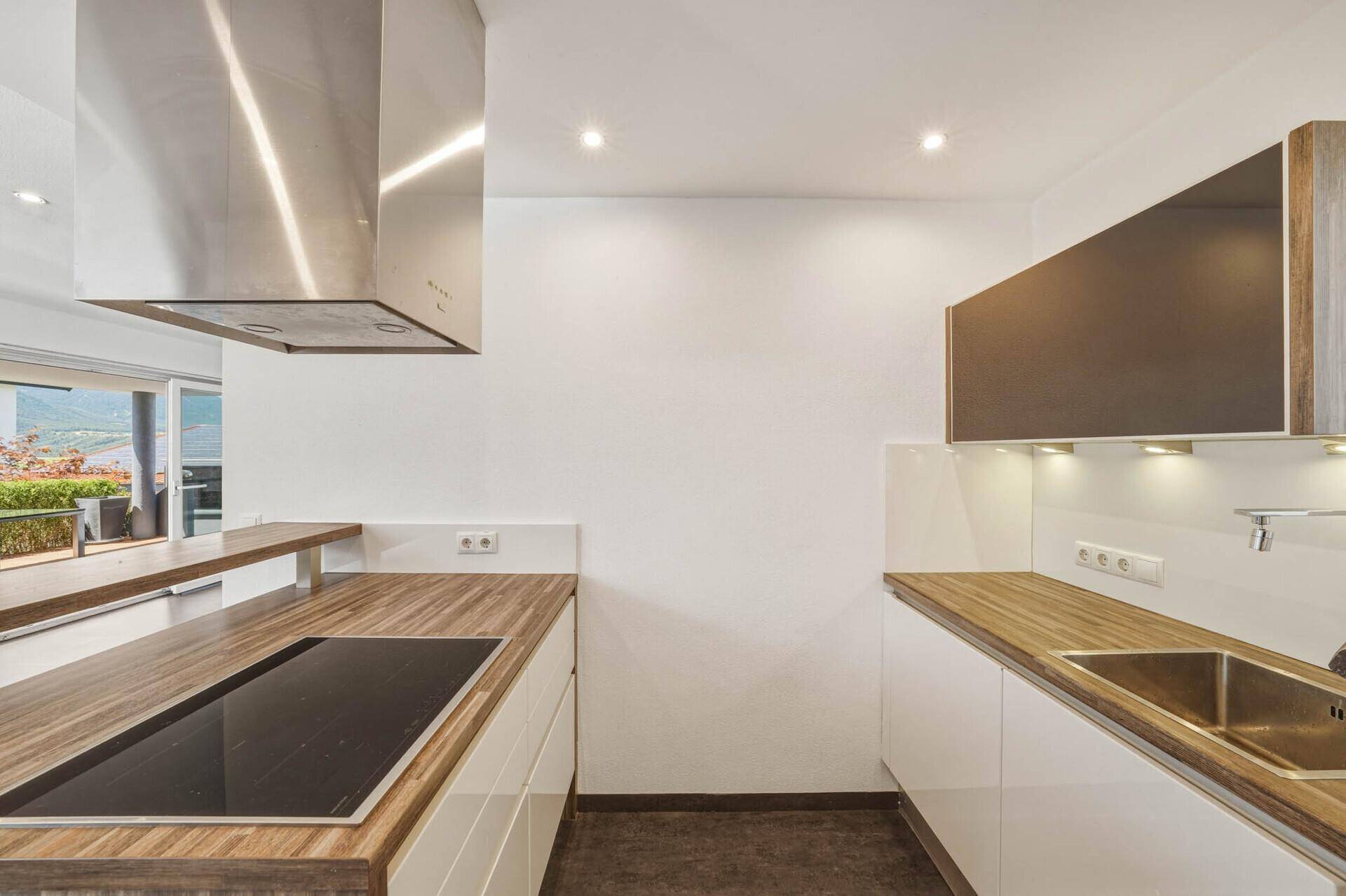 Küchenarbeitsplatte aus Holz mit integriertem Induktionskochfeld und Edelstahlspüle.