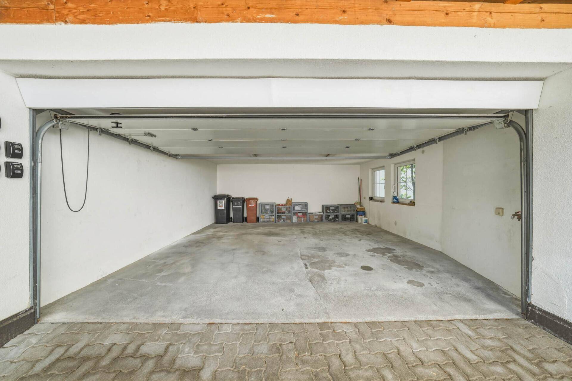 Geräumige leere Garage mit Betonboden und offenem Garagentor, bereit zur Nutzung.